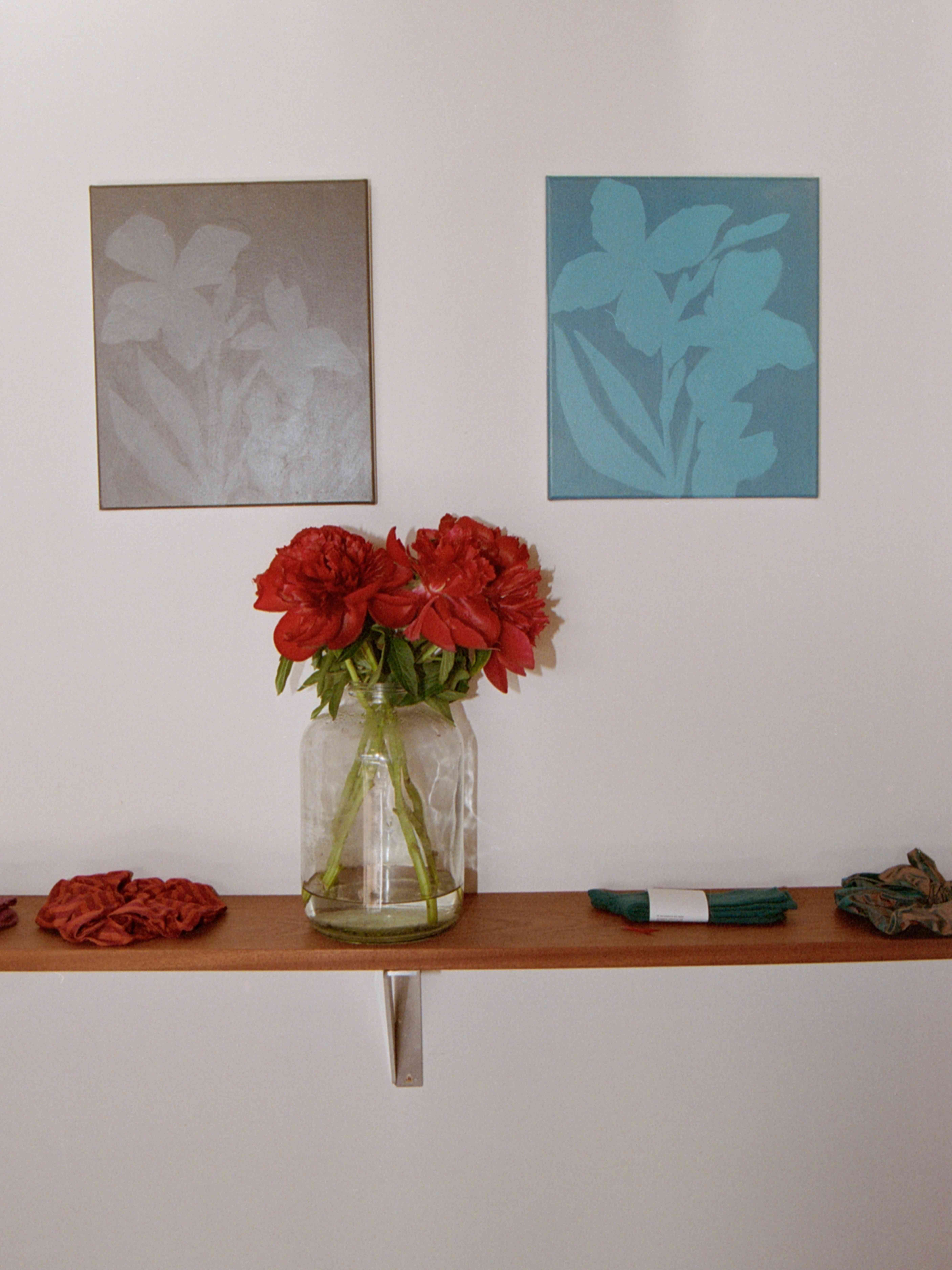 Briana Jamieson Iris paintings and a vase of red peonies on a shelf
