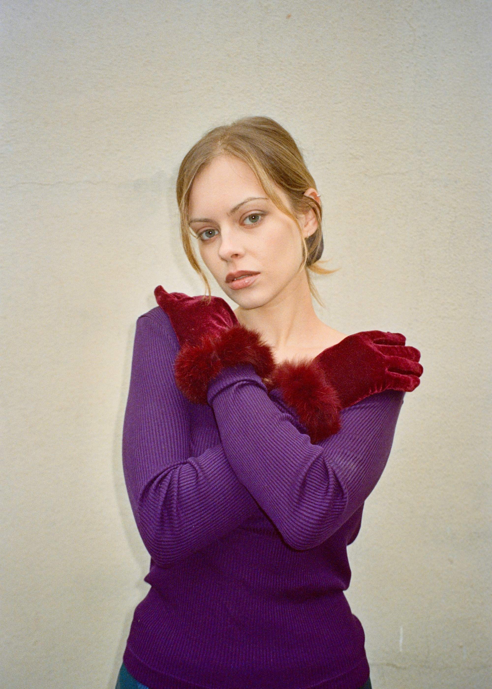 Model wearing velvet gloves and a violet knit top