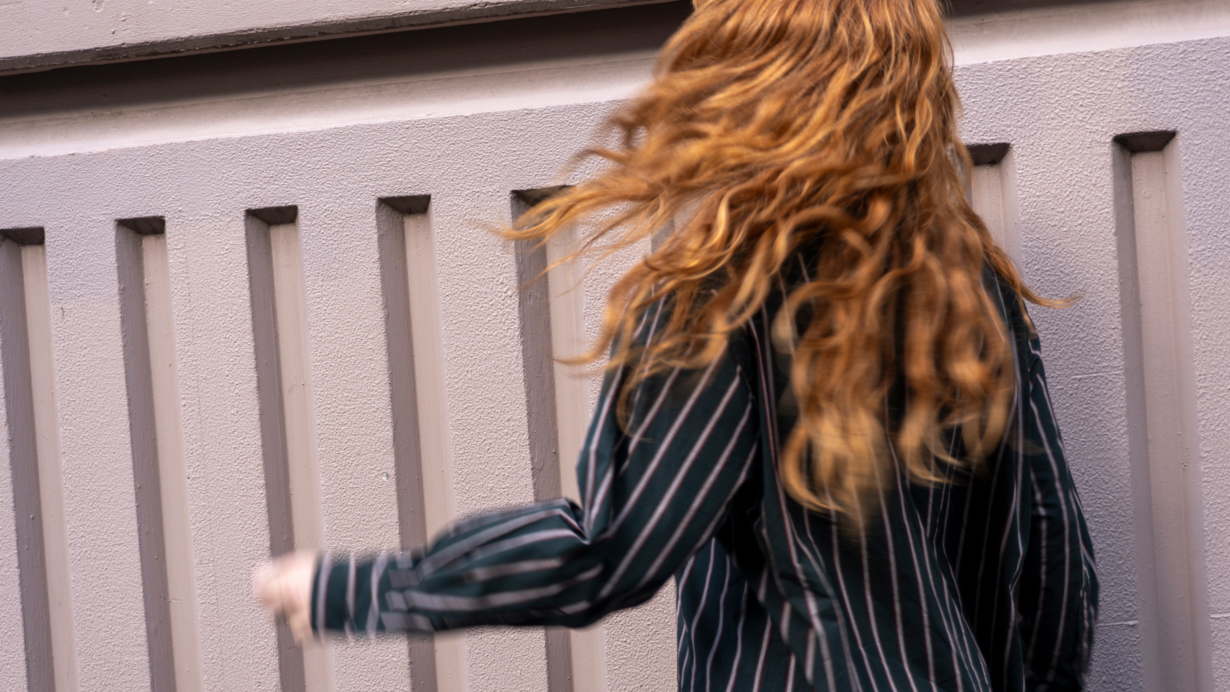 Model with long red hair wearing a green striped shirt