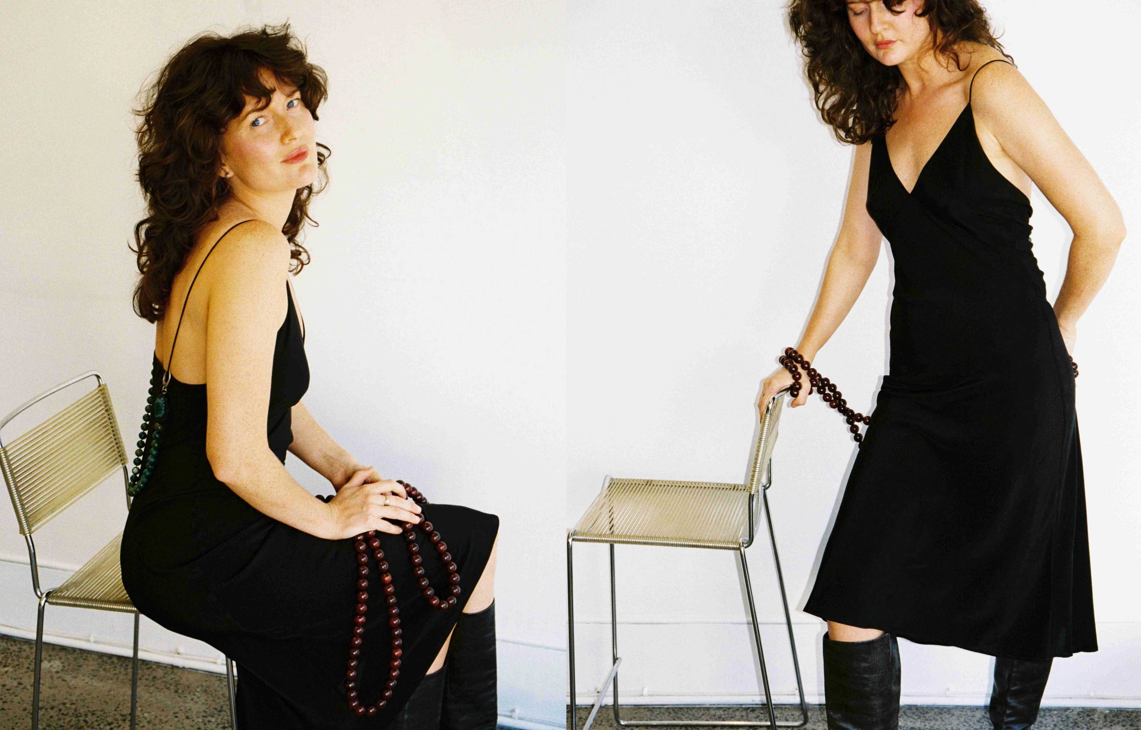 Model wearing black silk dress and holding beads