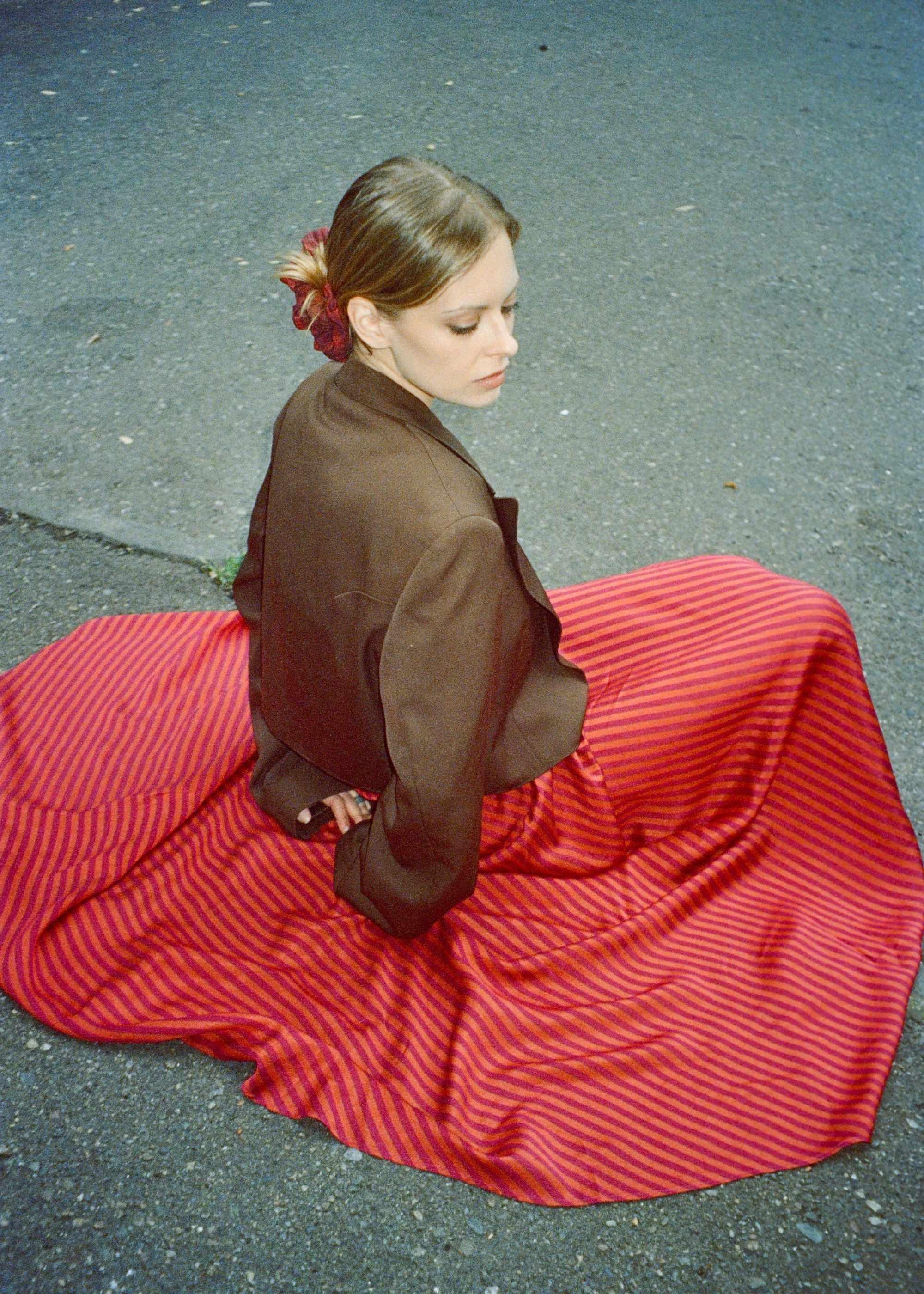 model wearing a bright stripe Suni skirt and brown vintage jacket