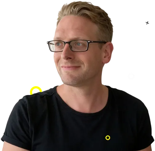 Man met kort blond haar en zwarte bril, gekleed in een zwart t-shirt, kijkend opzij op een zwarte achtergrond met gele en witte geometrische vormen.