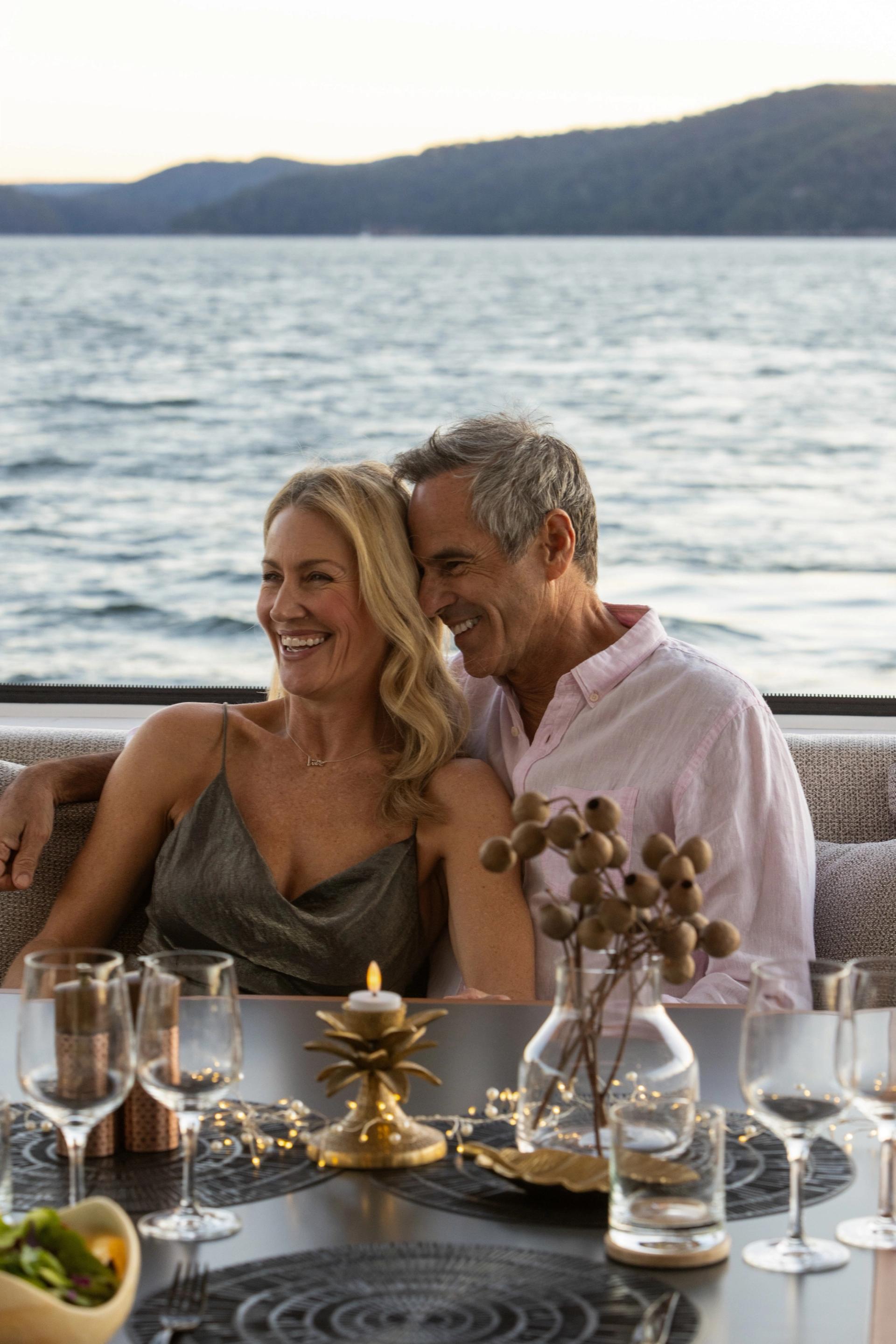 A couple share a candlelit dinner at dusk on board