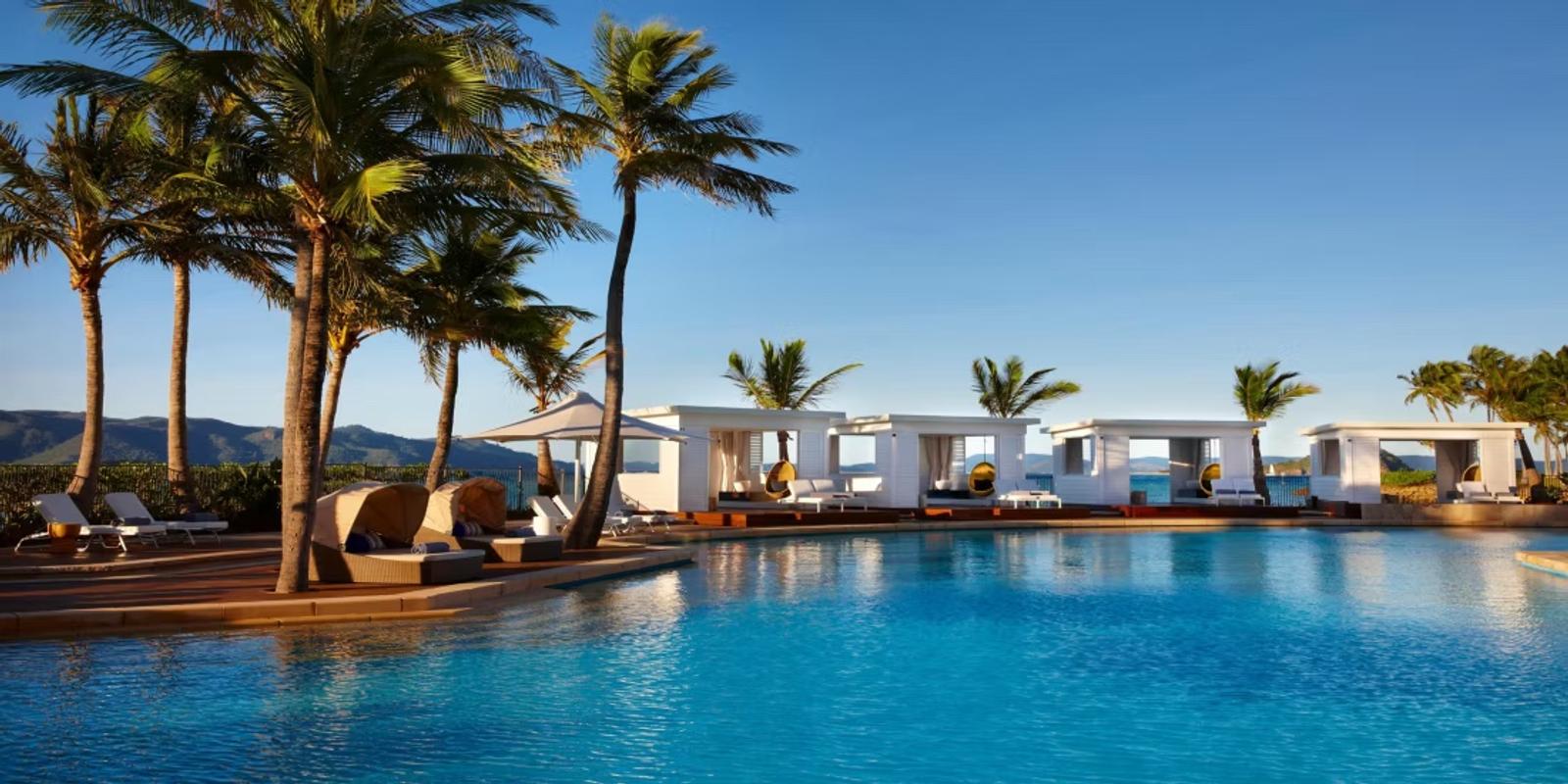 Hayman Pool — cabanas and palms at the water line