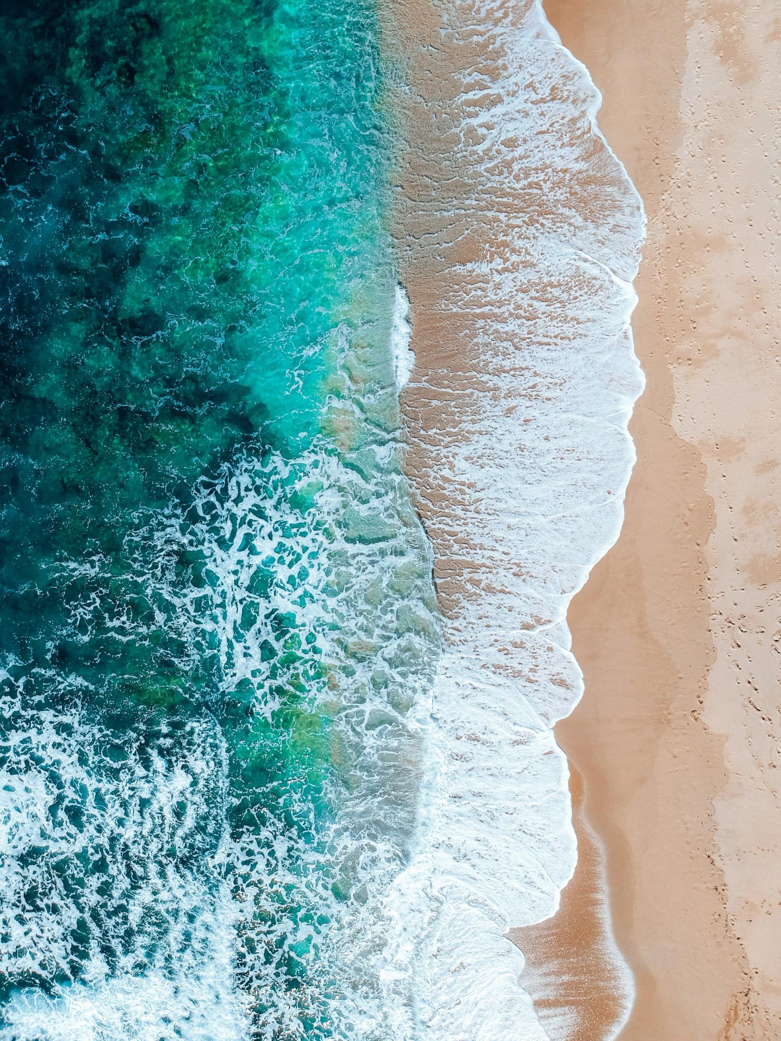 Turquoise water meeting golden sand from above