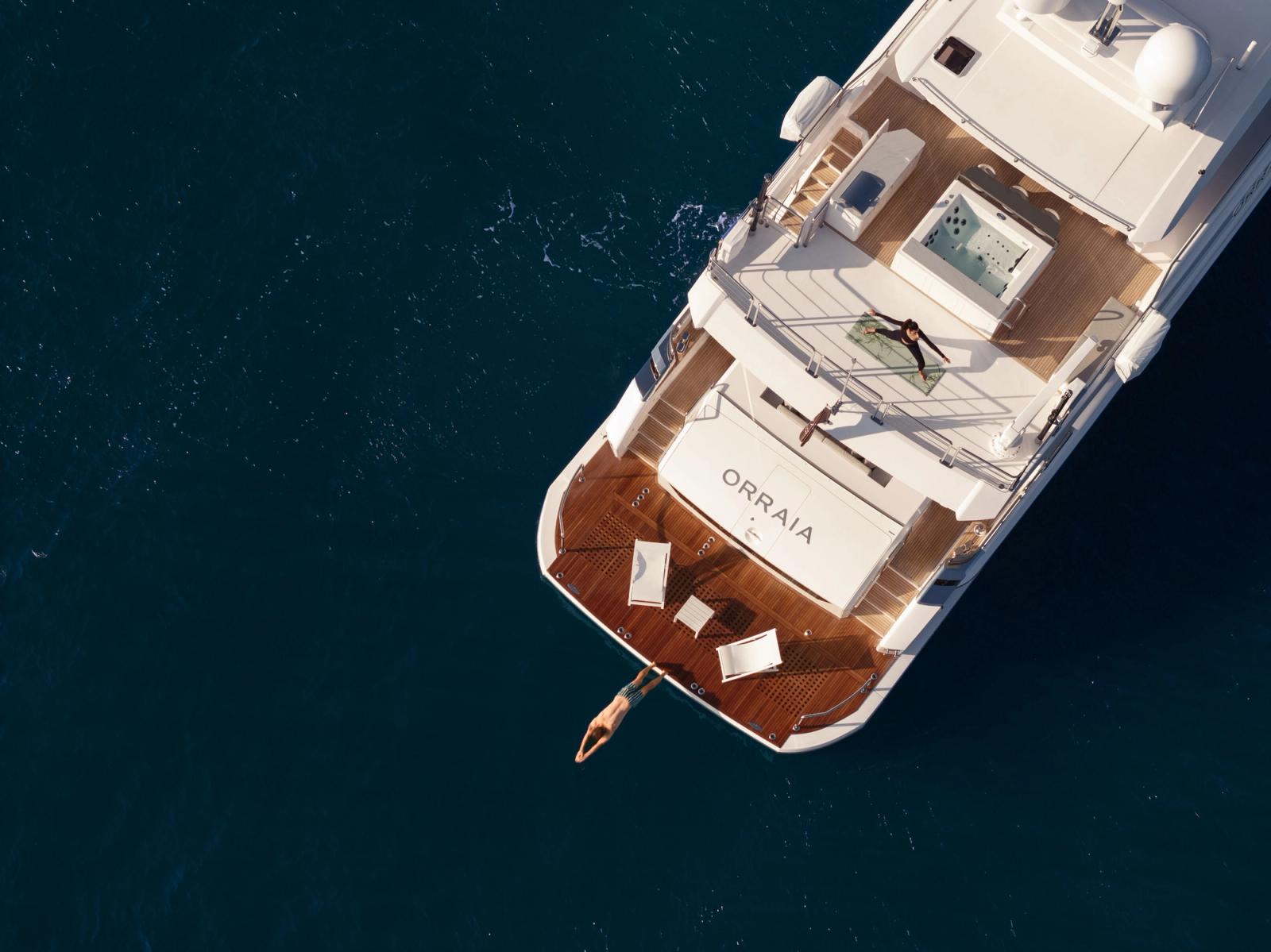 A guest swimming from the yacht's deck into clear blue water