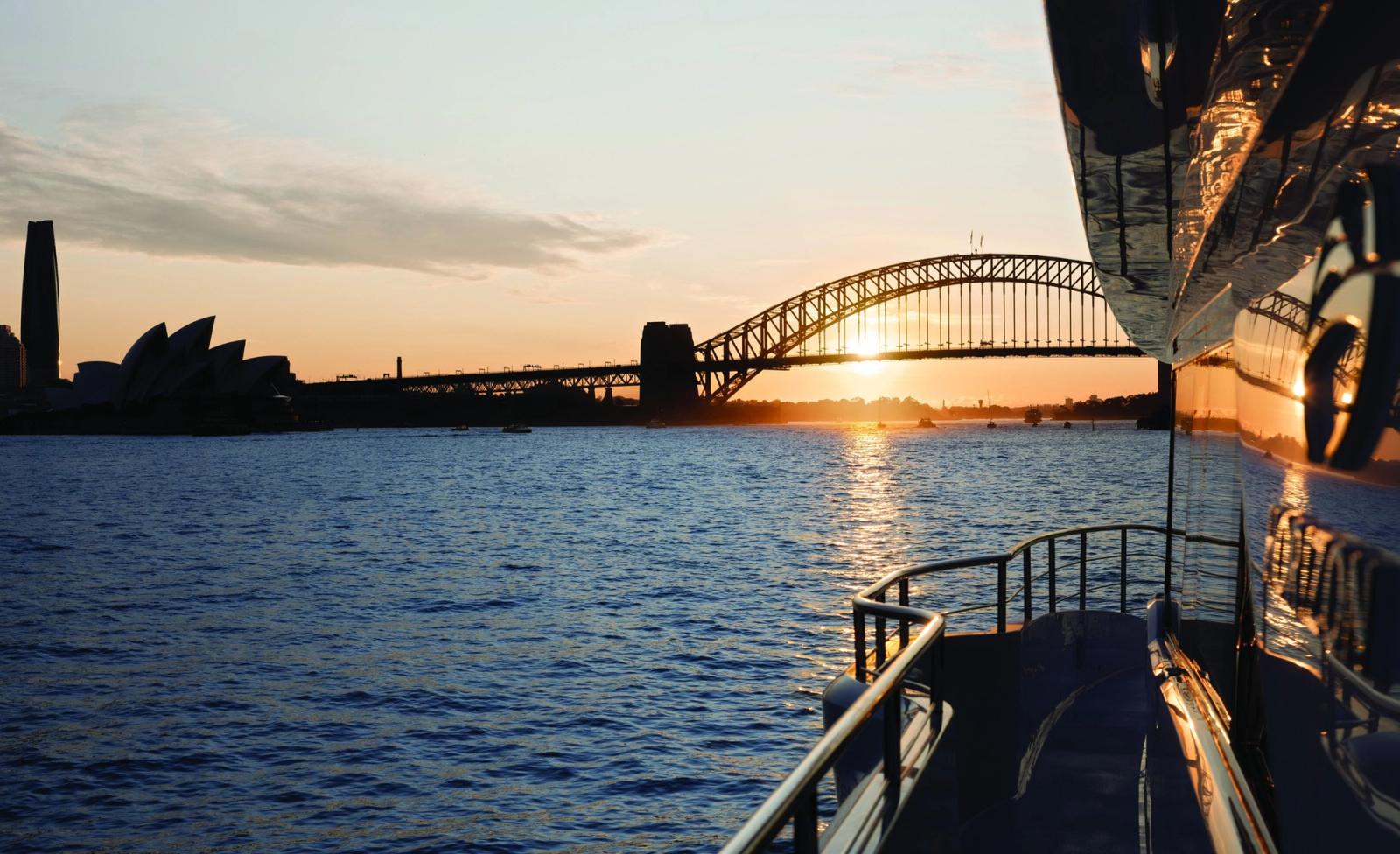 Sydney Harbour Bridge and the Opera House at golden sunset, seen from the deck of a yacht