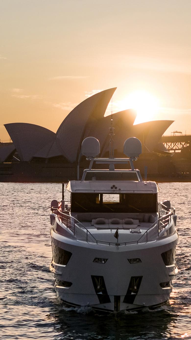 Yacht cruising toward the Sydney Opera House at sunset