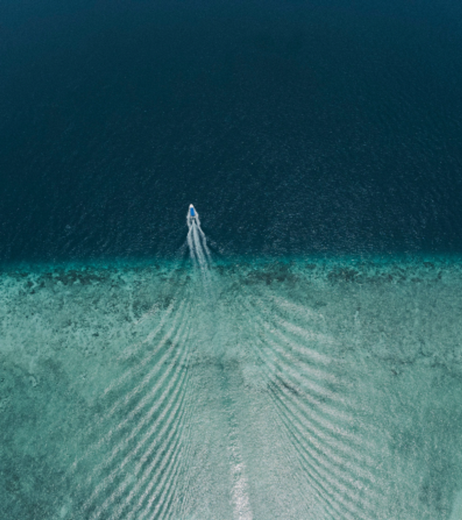 A tender crossing turquoise reef shallows into deep water