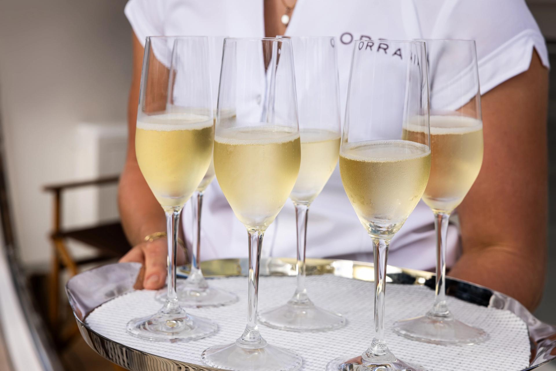 A tray of champagne flutes held by crew in ORRAIA whites