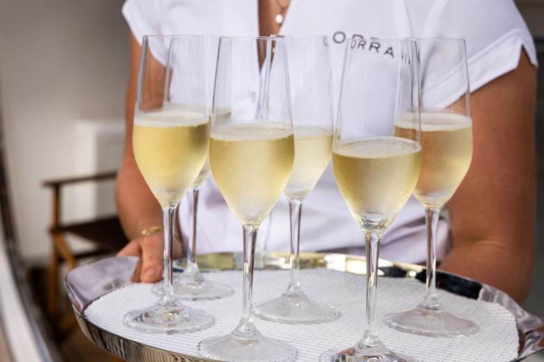 A tray of champagne flutes held by crew in ORRAIA whites
