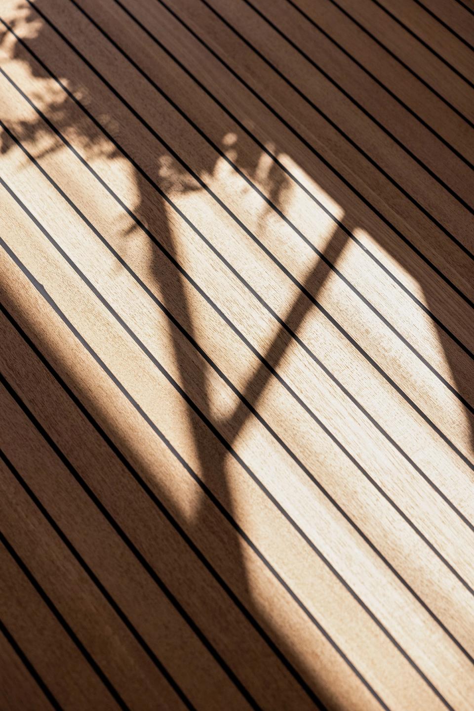 Sunlight and shadow patterns across a teak yacht deck