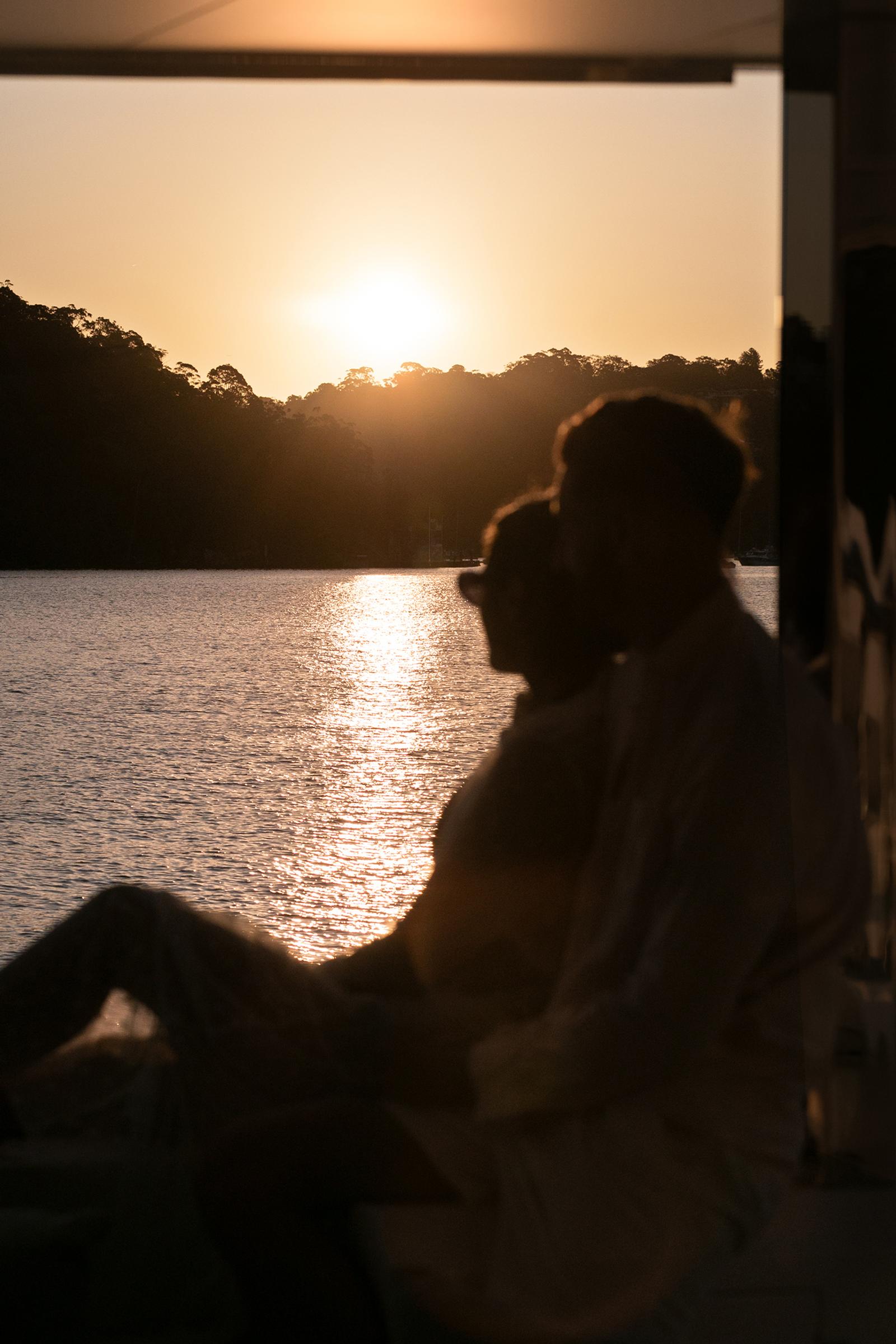 Guests on deck at dusk as the sun sets over the water at an ORRAIA summer soirée