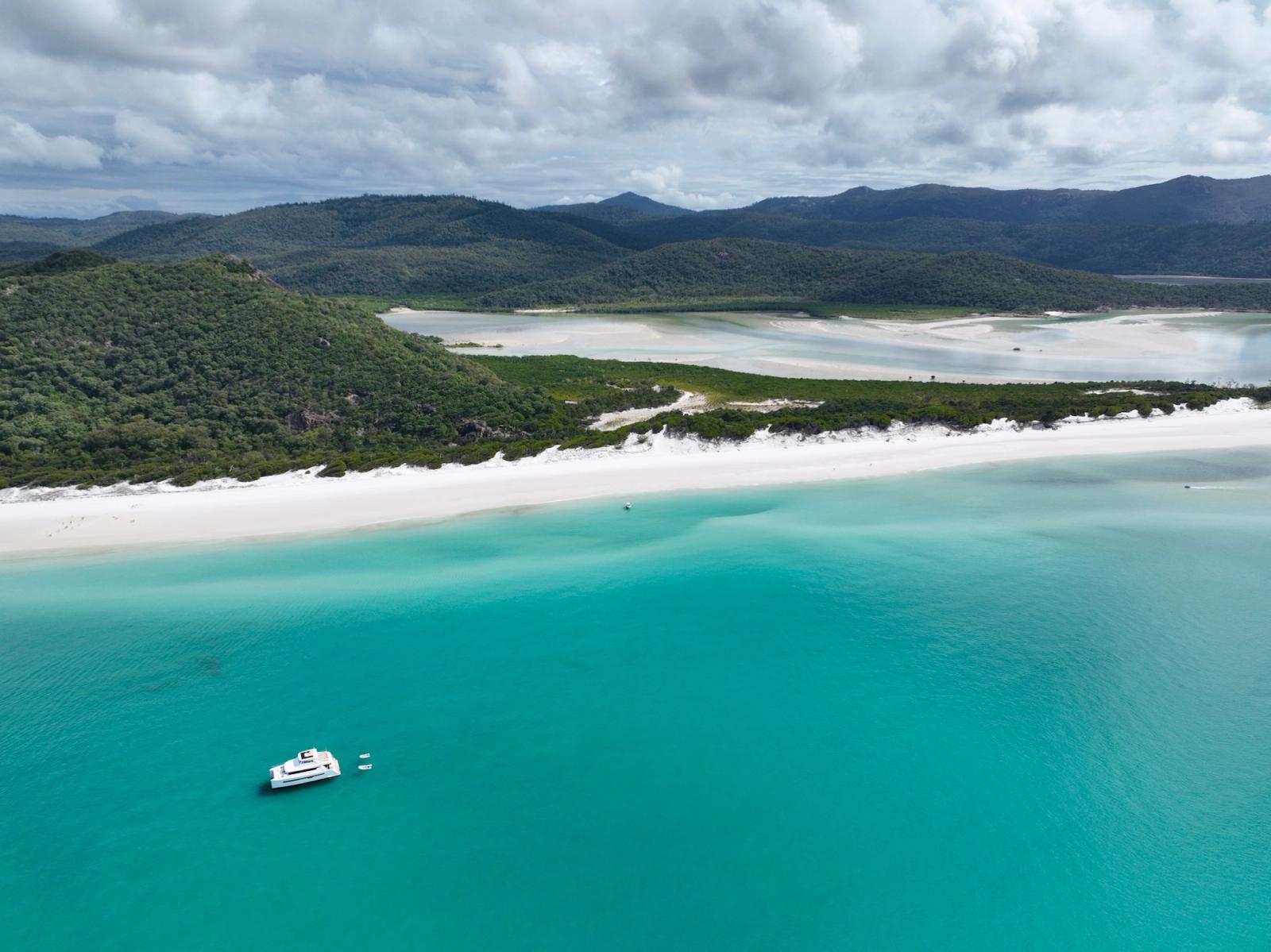 A catamaran and tender at anchor off the white sand of Whitehaven Beach