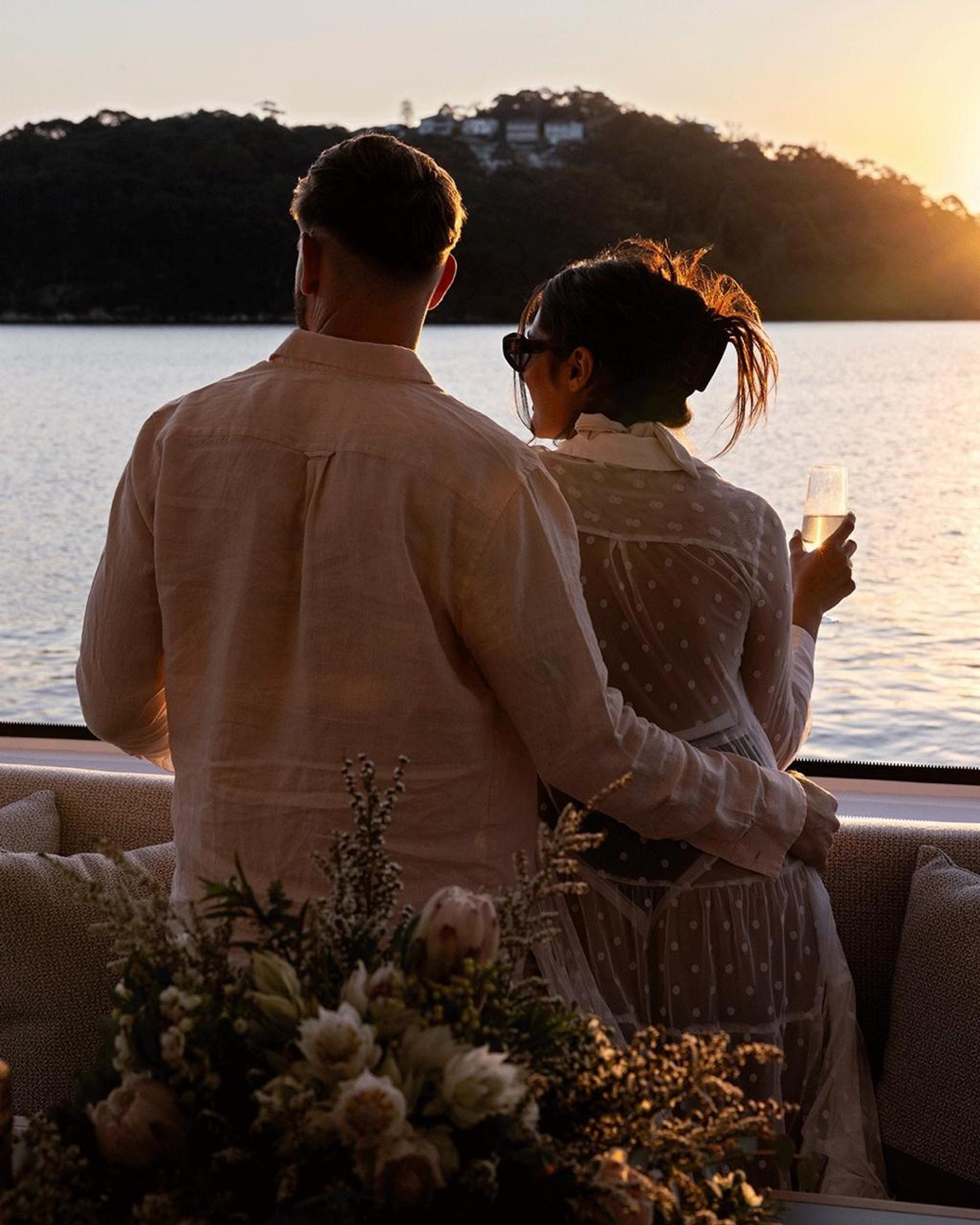 A couple embracing on the aft deck watching the sunset over the water