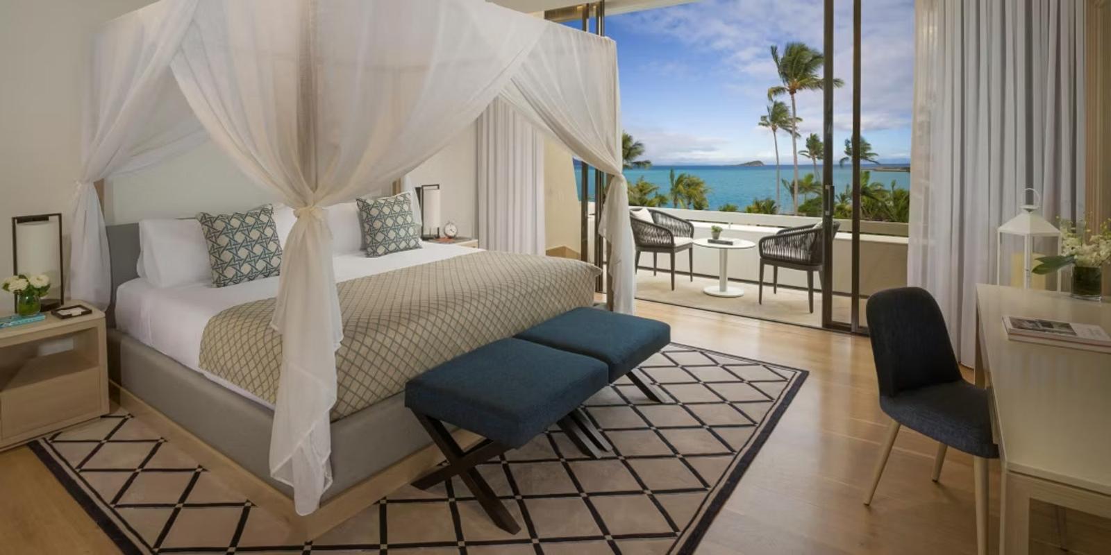Suite bedroom with canopy bed and ocean balcony