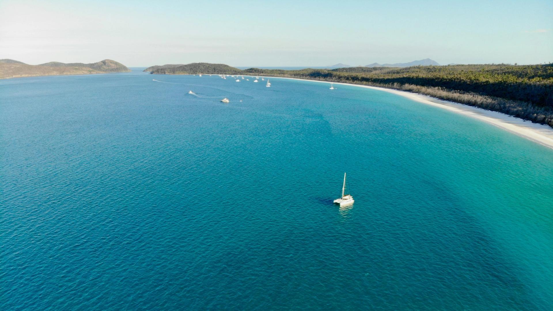 Orraia cruising through the blue waters of the Whitsundays, seen from the air