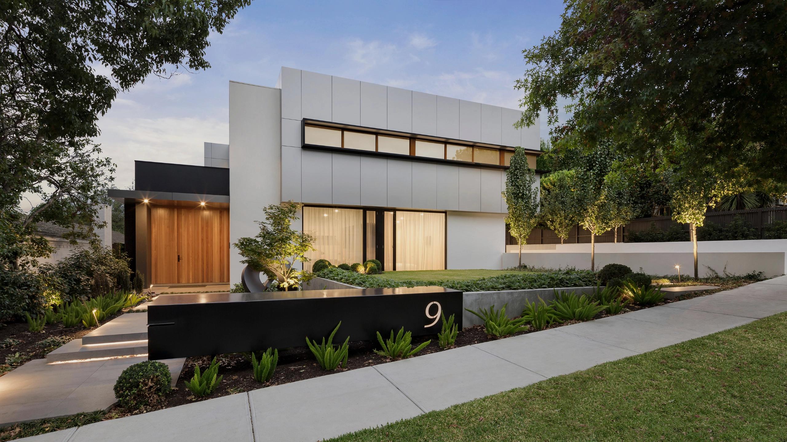 Modern luxury house exterior with landscaped front garden and pathway.