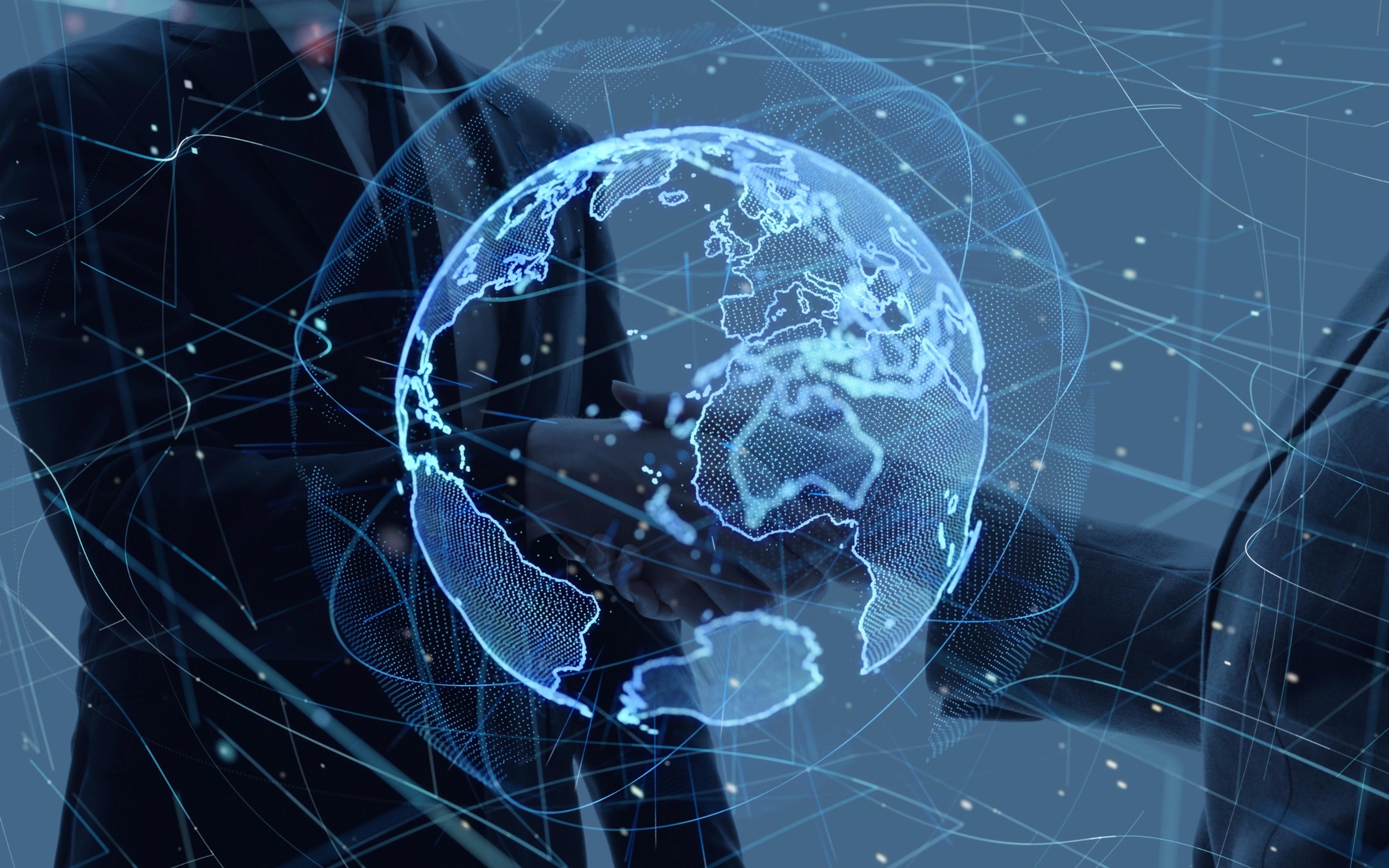 Two suited professionals shake hands enclosing a glowing blue holographic Earth globe