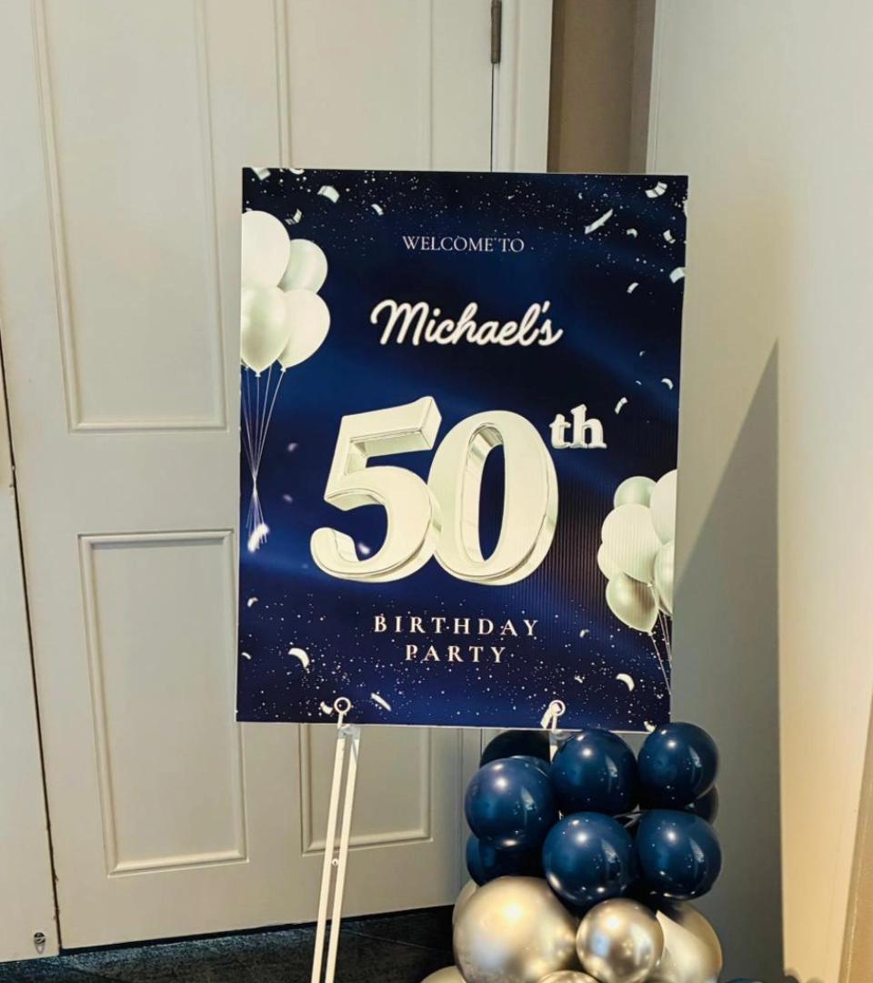 WELCOME TO Michael's 50th BIRTHDAY PARTY sign with white balloons and a balloon arch.