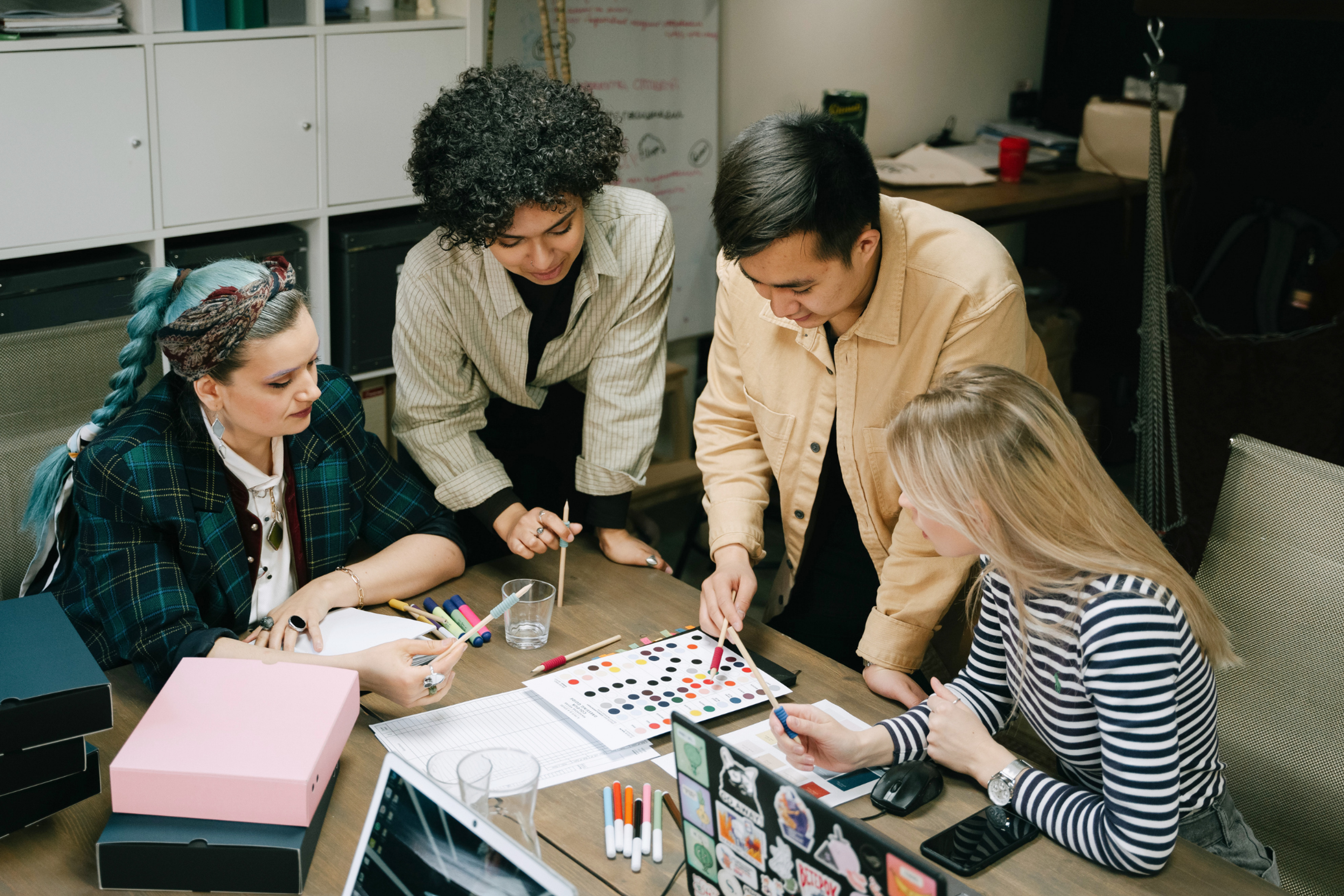 A team of designers collaborating at a table, reviewing color palettes and design materials while discussing branding and creative work together.