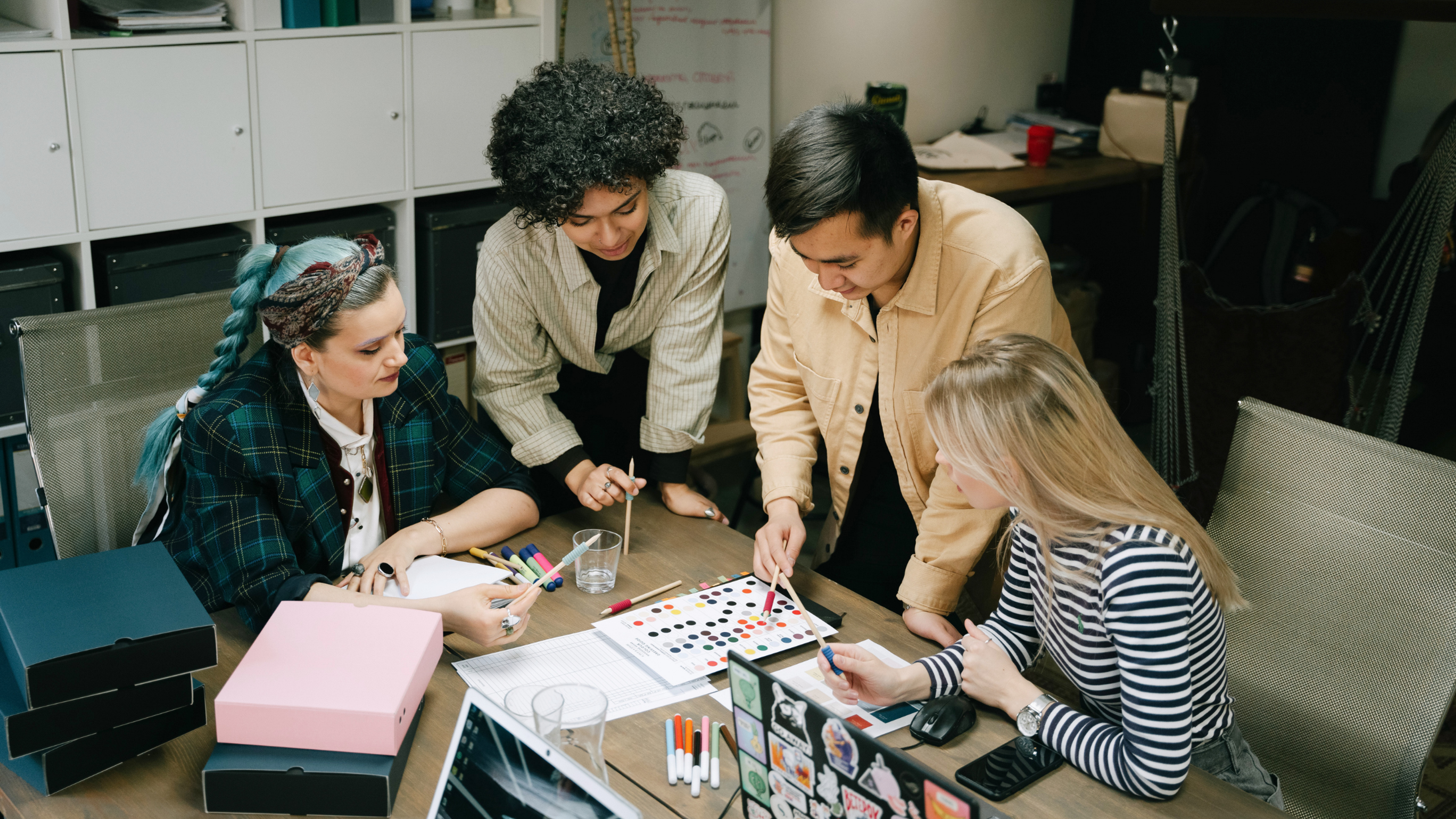 A team of designers collaborating at a table, reviewing color palettes and design materials while discussing branding and creative work together.