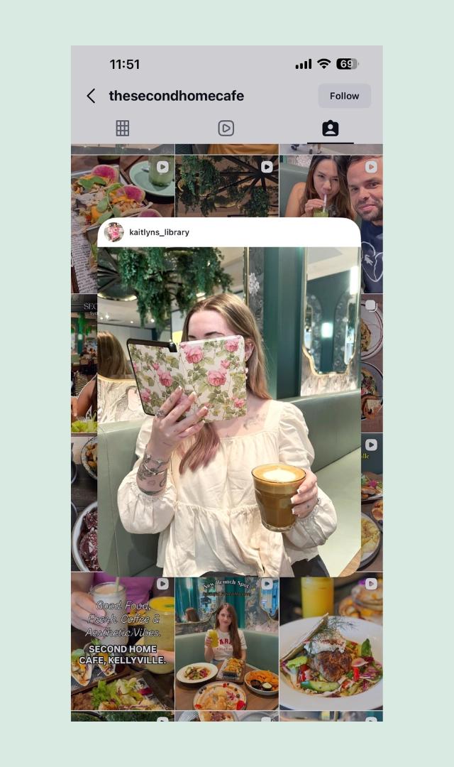 Katlyn B (@katlynb) reads floral book holding iced coffee in plant-filled cafe booth amid food photos