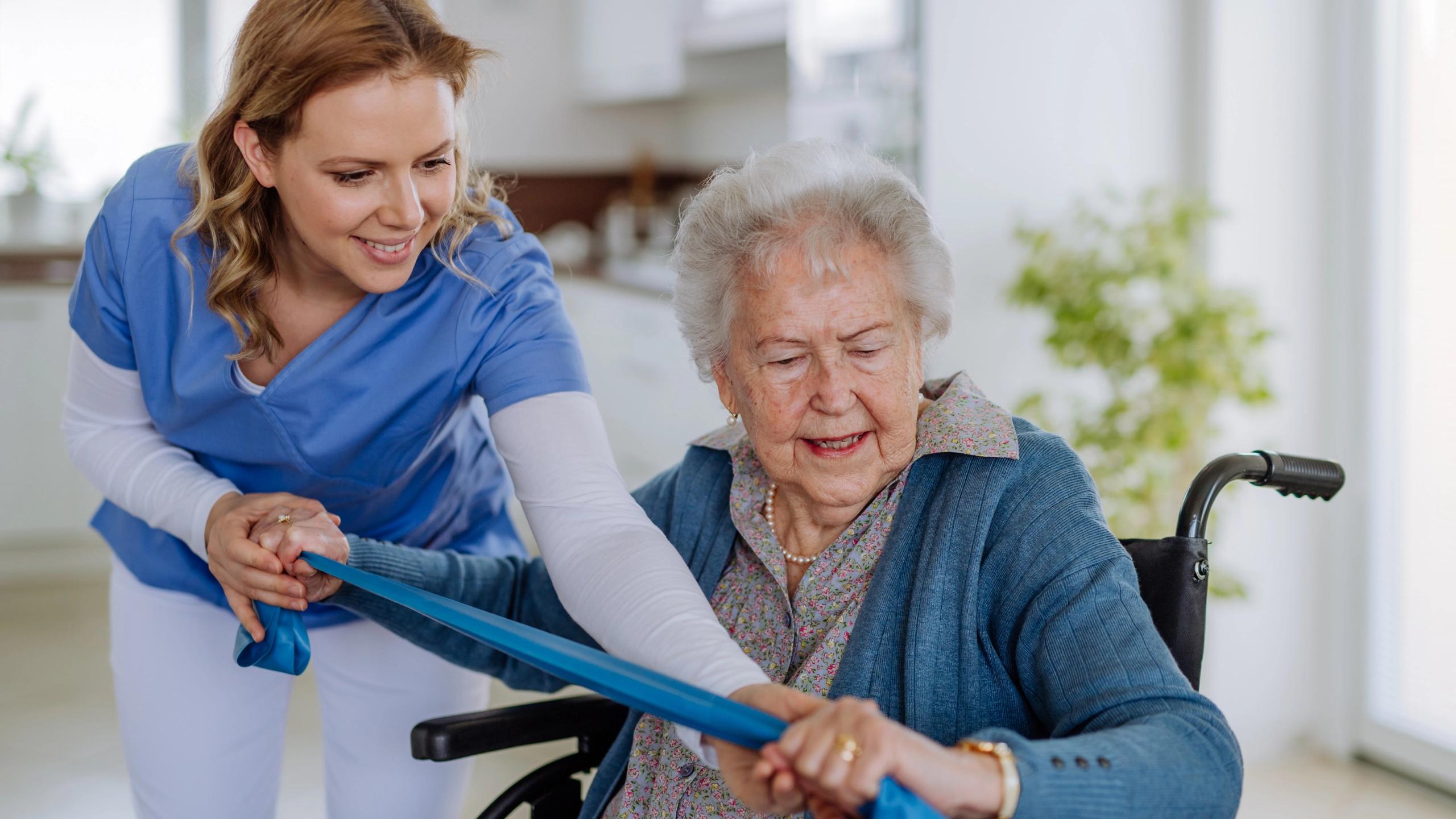Carer helping an elderly with her strectching