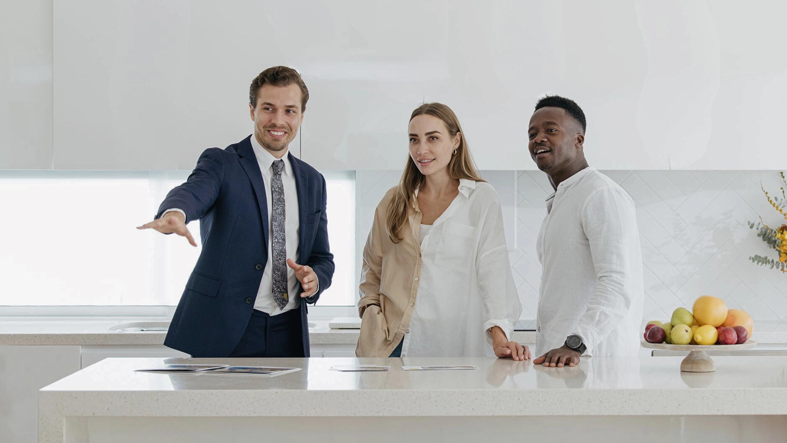 Real estate agent showing a modern kitchen to a couple during a property inspection.