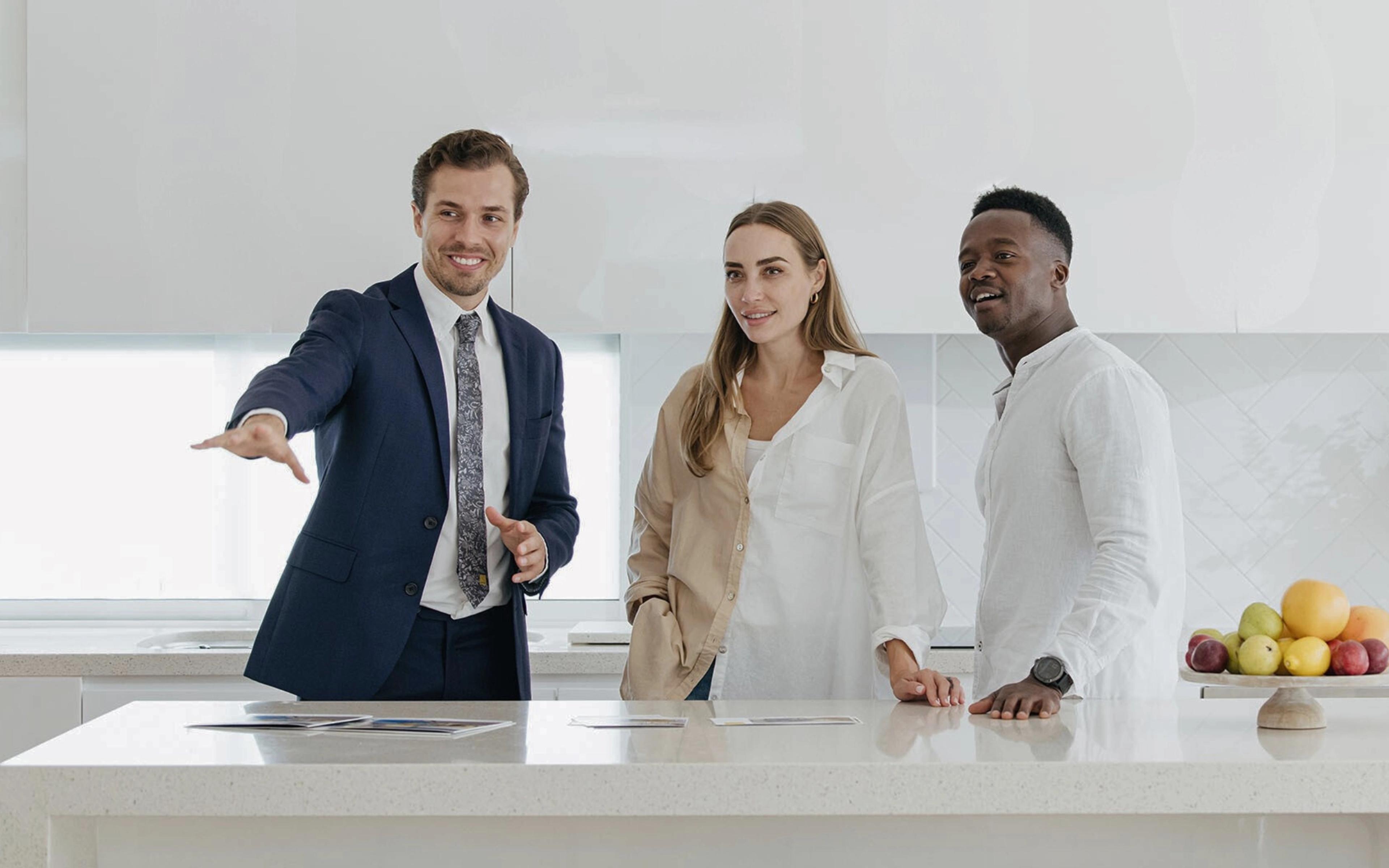 Real estate agent showing a modern kitchen to a couple during a property inspection.