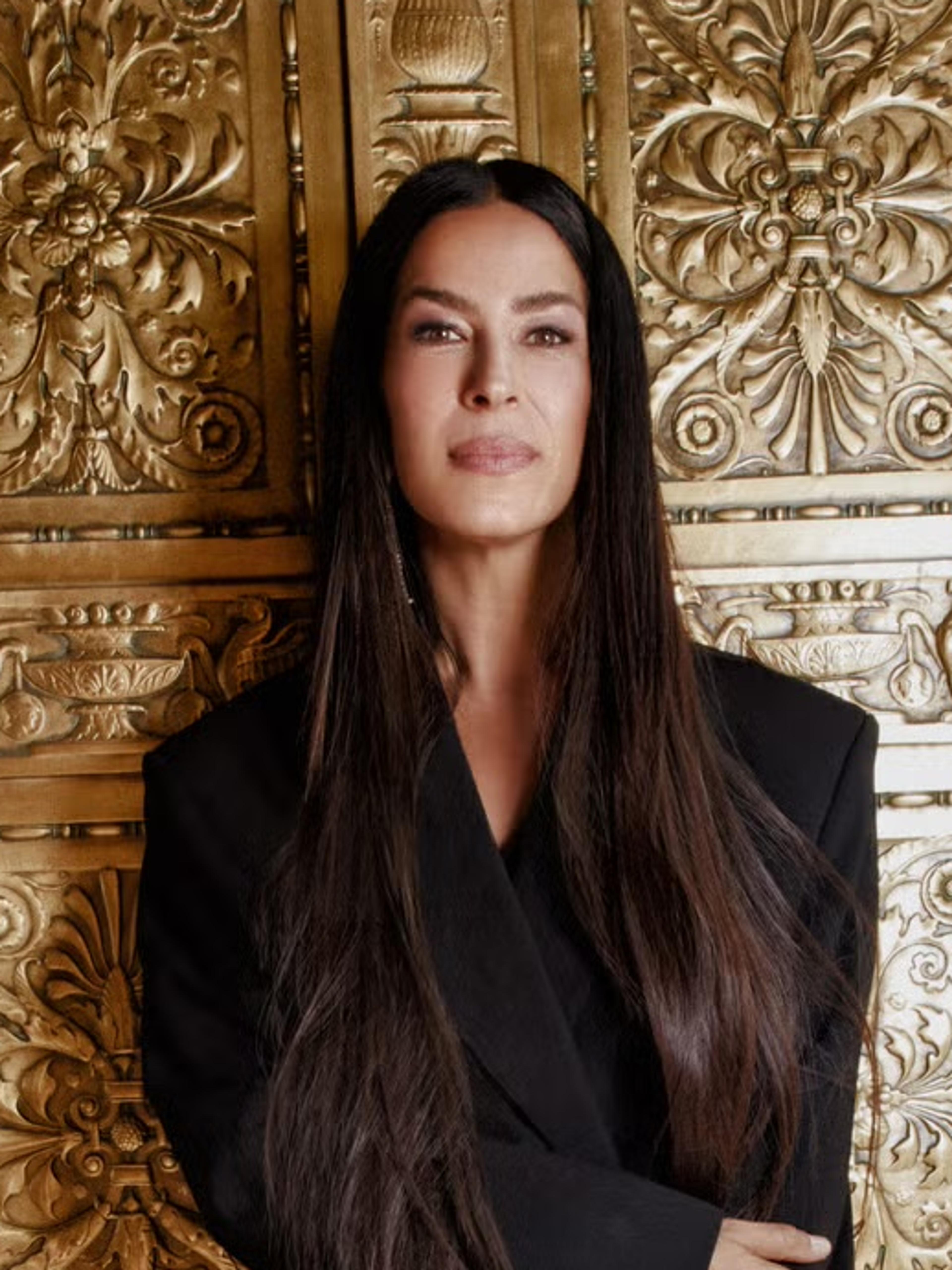 Rebecca Minkoff in a black blazer dress and knee-high boots against an ornate gold panelled door