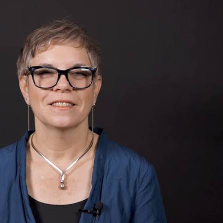Dr. Tovah Klein smiling, in black-rimmed glasses and a blue jacket