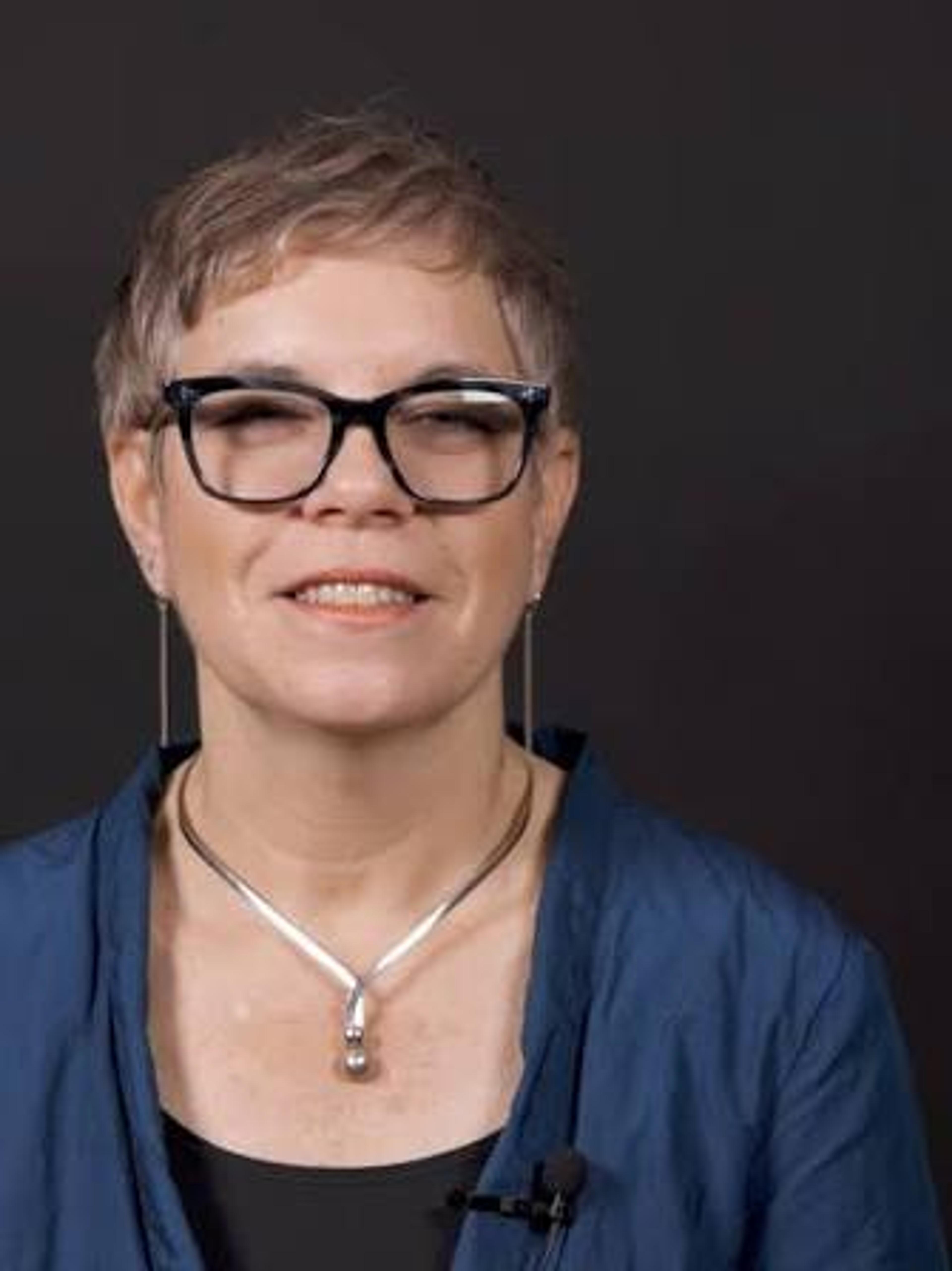 Dr. Tovah Klein smiling, in black-rimmed glasses and a blue jacket