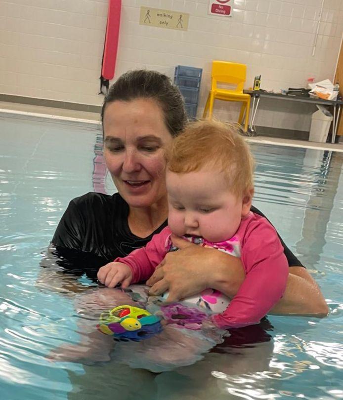 A therapist supporting a baby in the hydrotherapy pool during a play-based session