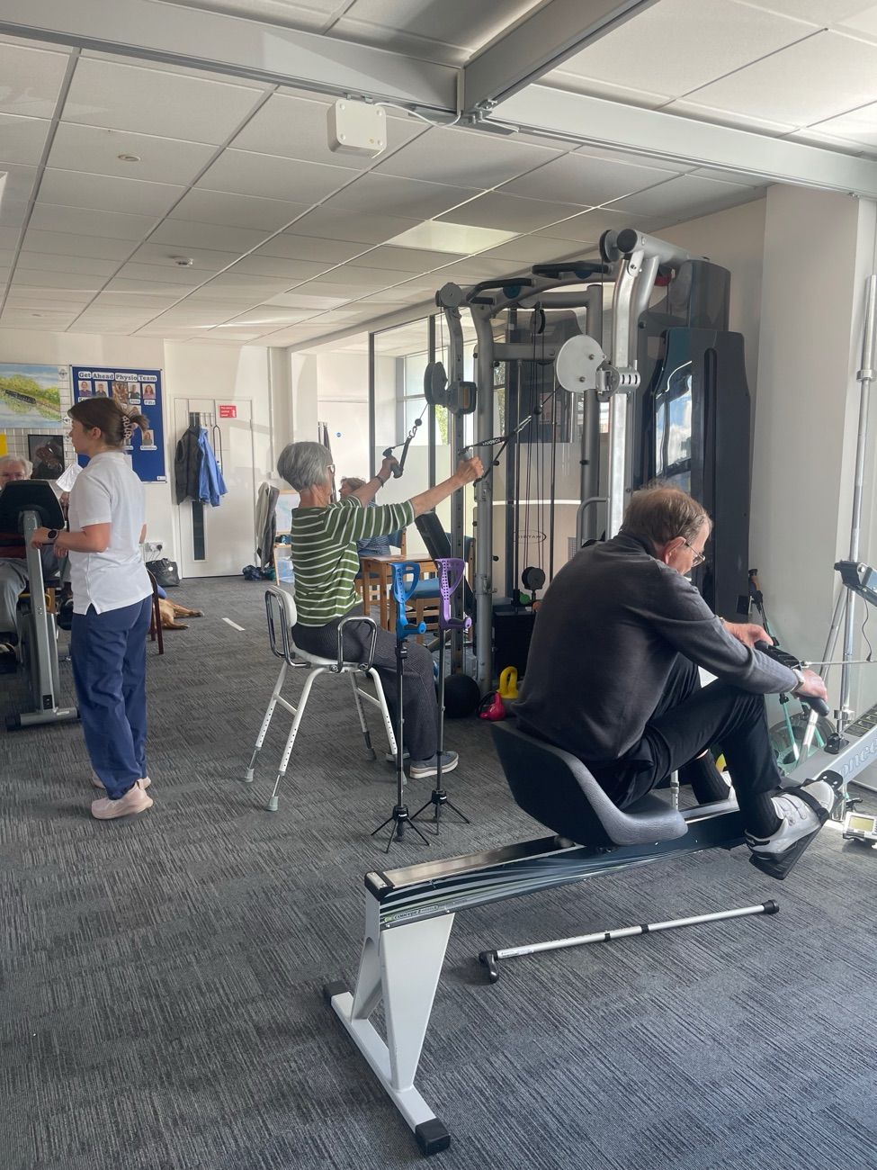Members of the adult exercise group using the cable machine and rowing machine in the accessible gym