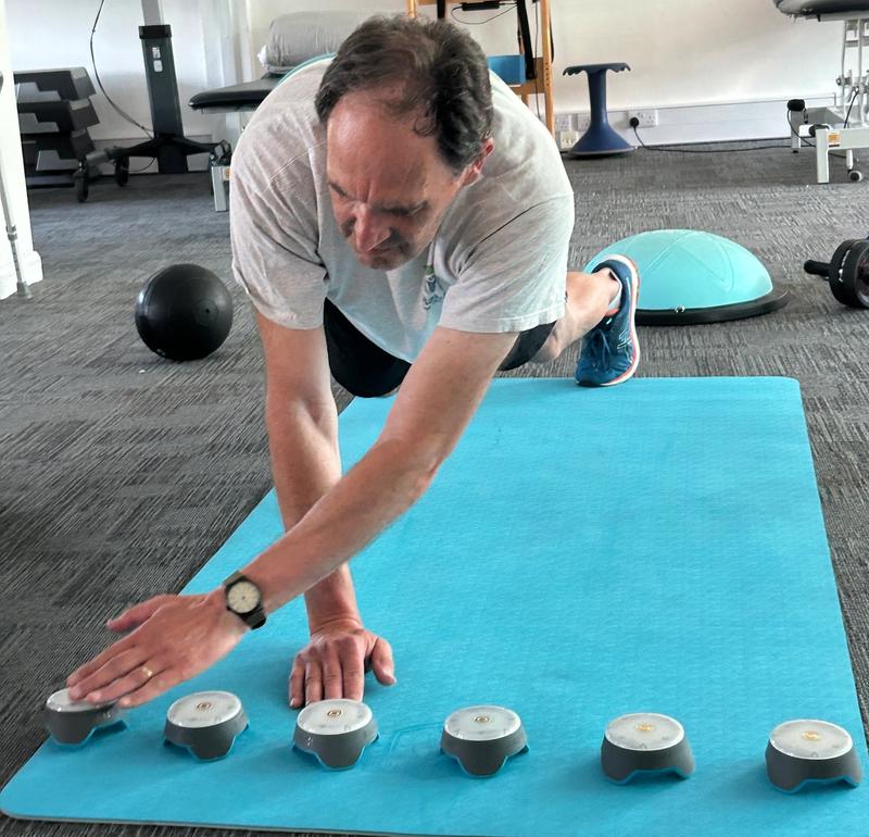 A client reaching for a row of reaction pods from a press-up position on the mat
