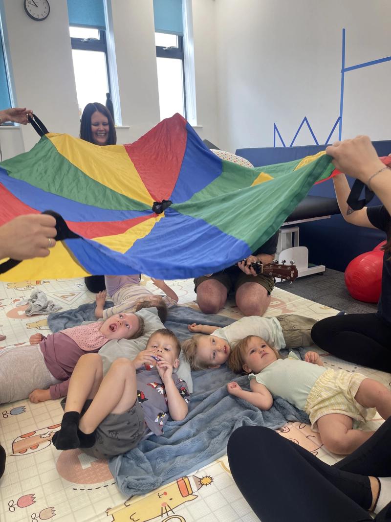 Babies lying under a play parachute during a Music and Movement session