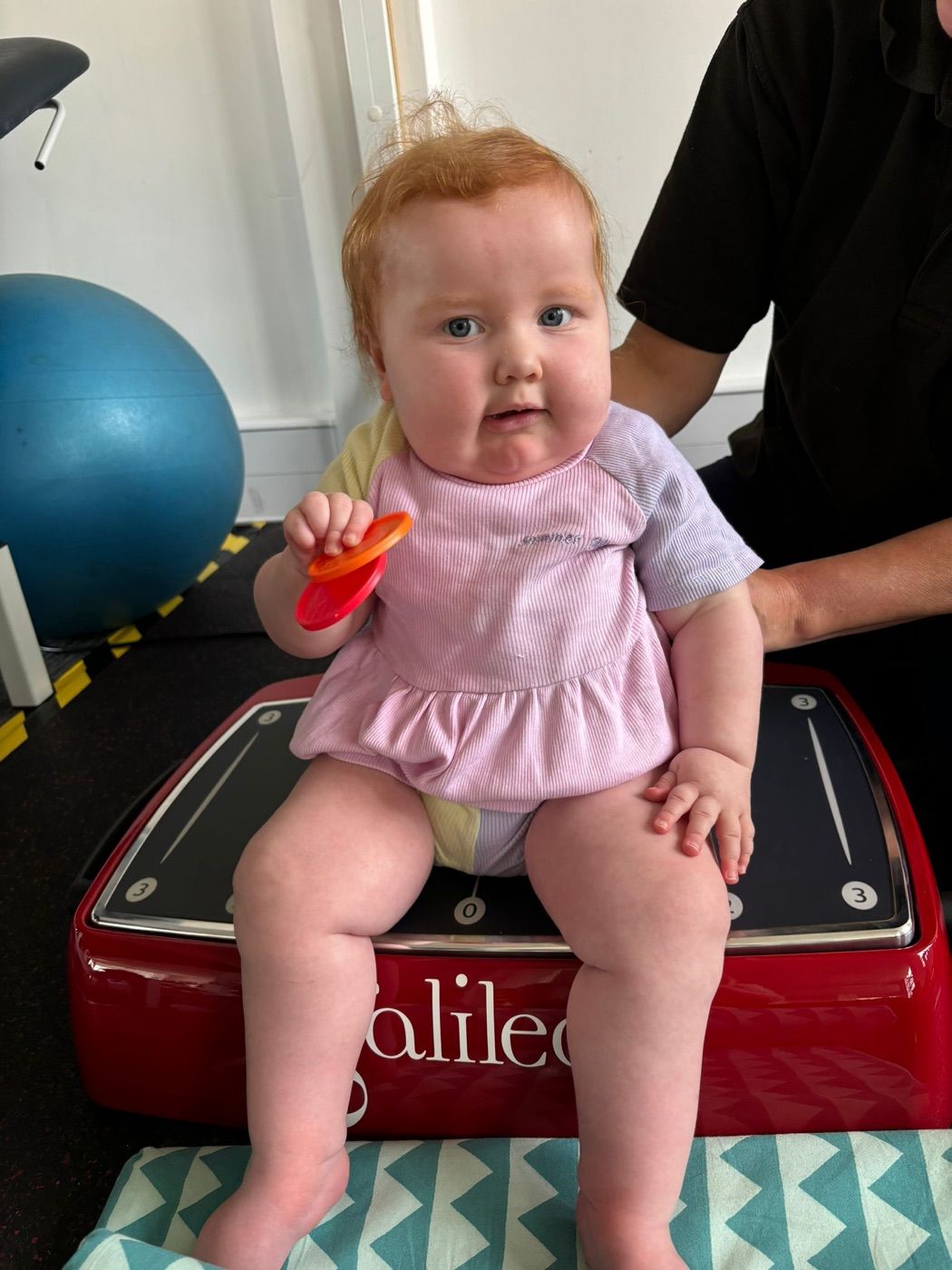 A child using the Galileo vibration plate with a physiotherapist supporting them