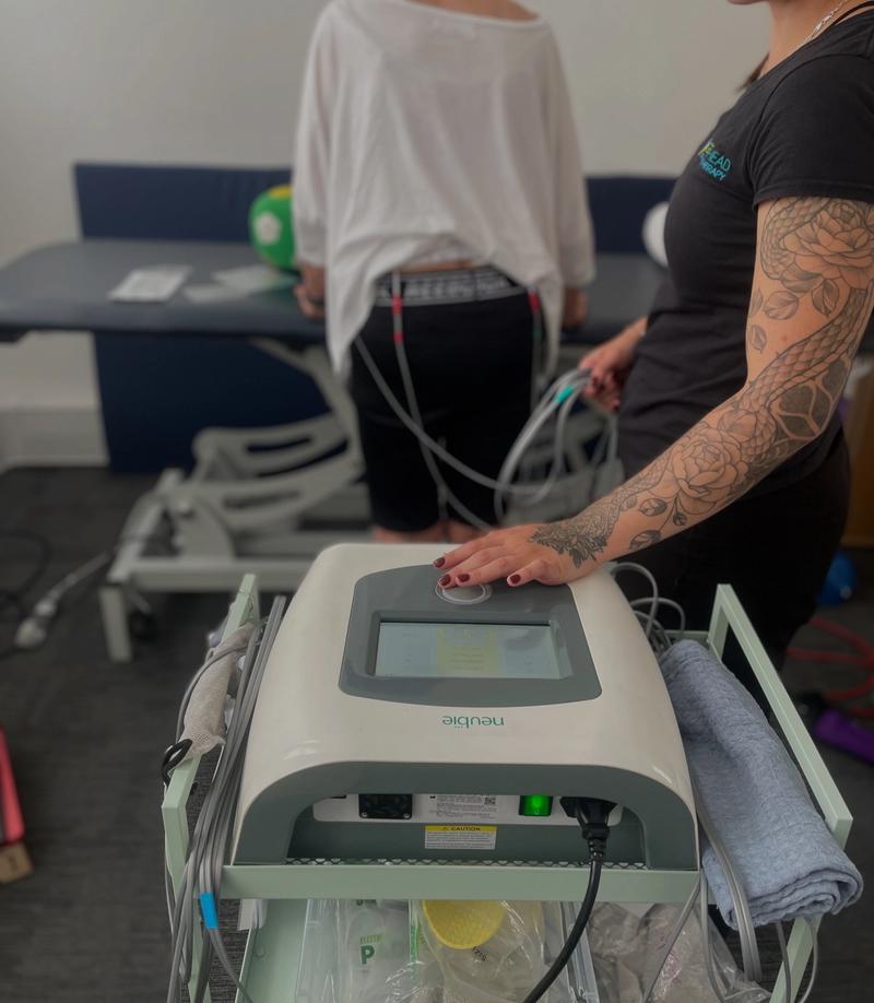 A physiotherapist operating the Neubie console during a treatment session