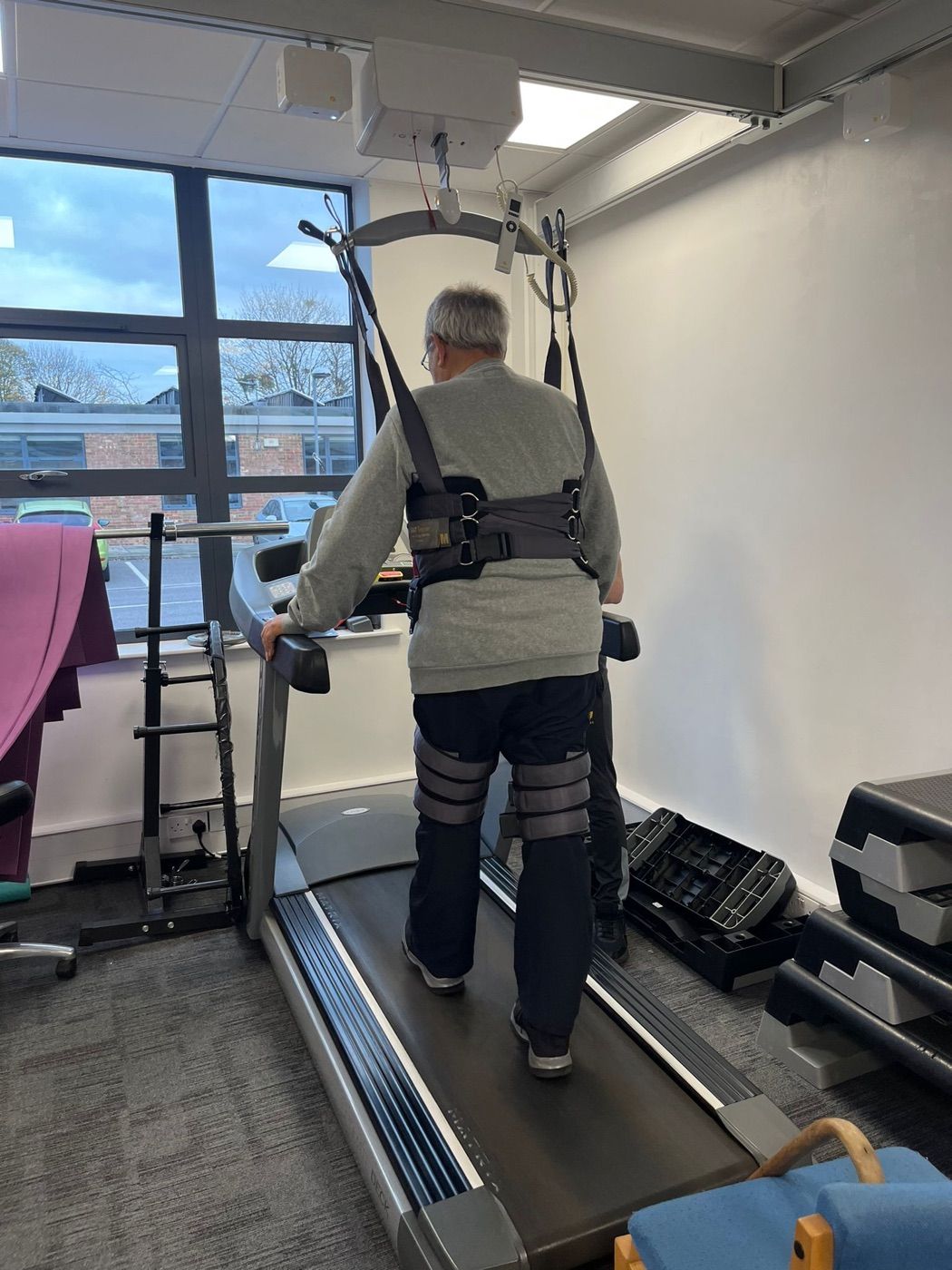 The ceiling-track hoist and support harness set up above the treadmill