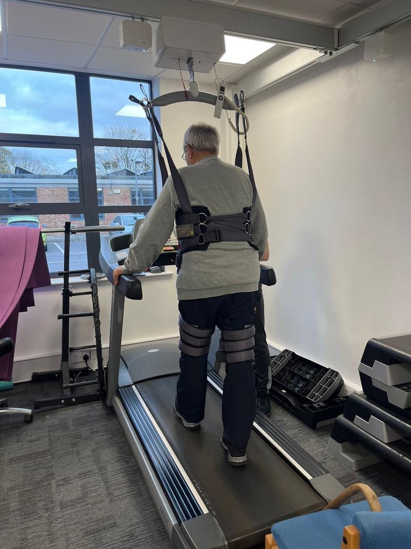The ceiling-track hoist and support harness set up above the treadmill