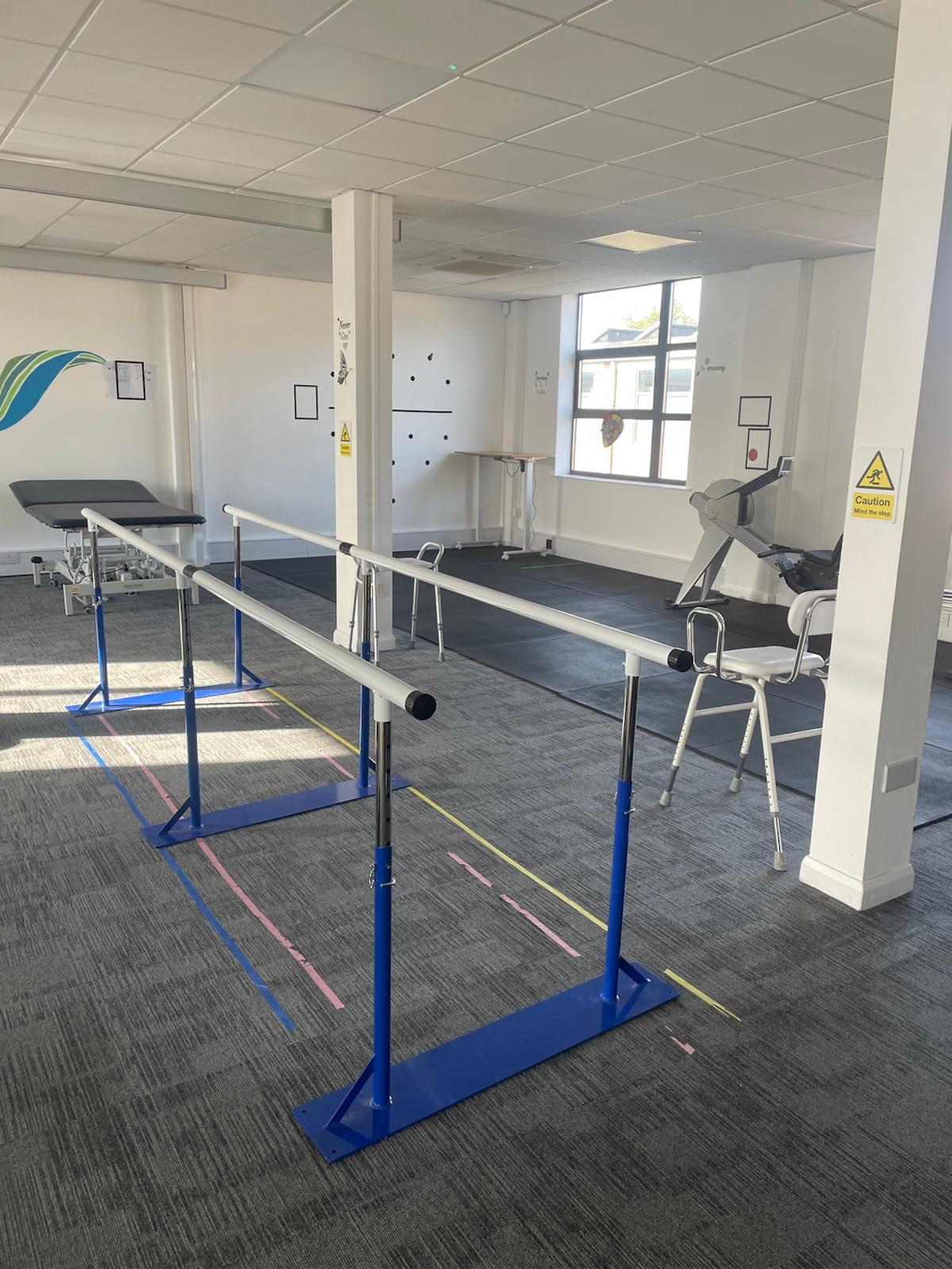 A client walking on the treadmill in a support harness while a physiotherapist assists