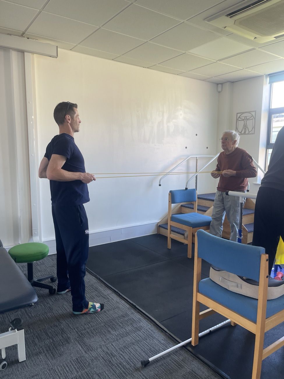 A physiotherapist supporting a group member with a resistance bar exercise