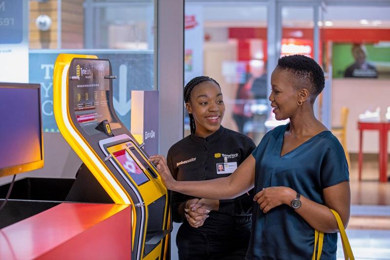 A member of staff helps a customer to use an instore atm
