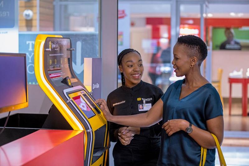 A member of staff helps a customer to use an instore atm