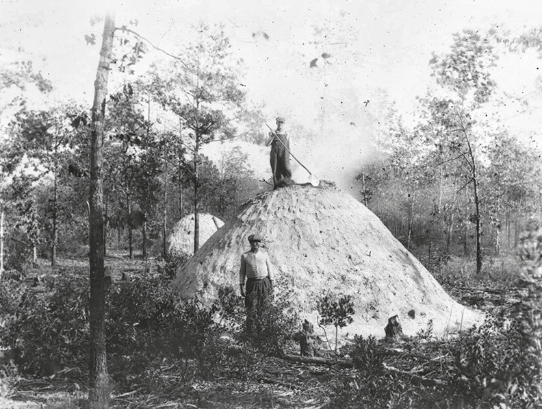 B&W photograph of past charcoal producing method using mounds of sand as a furnace