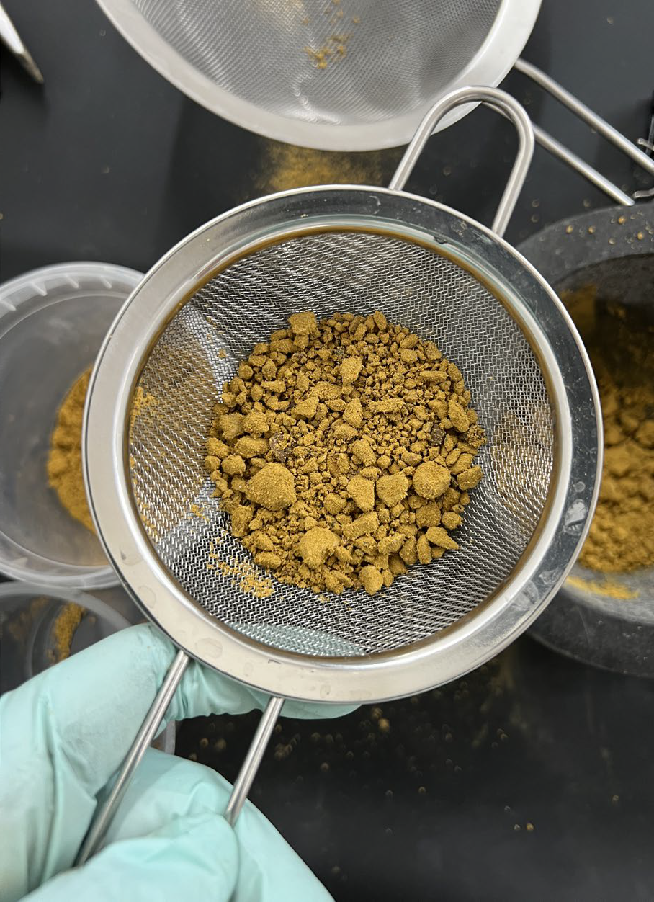 Metal sieve containing particles of yellow brick dust