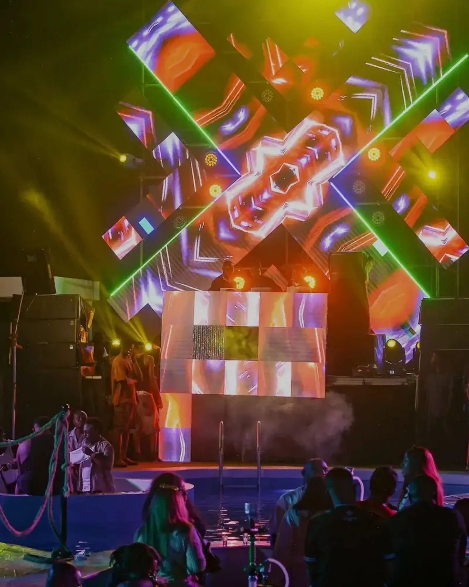 The stage at night, LED rigs lit, a crowd by the pool