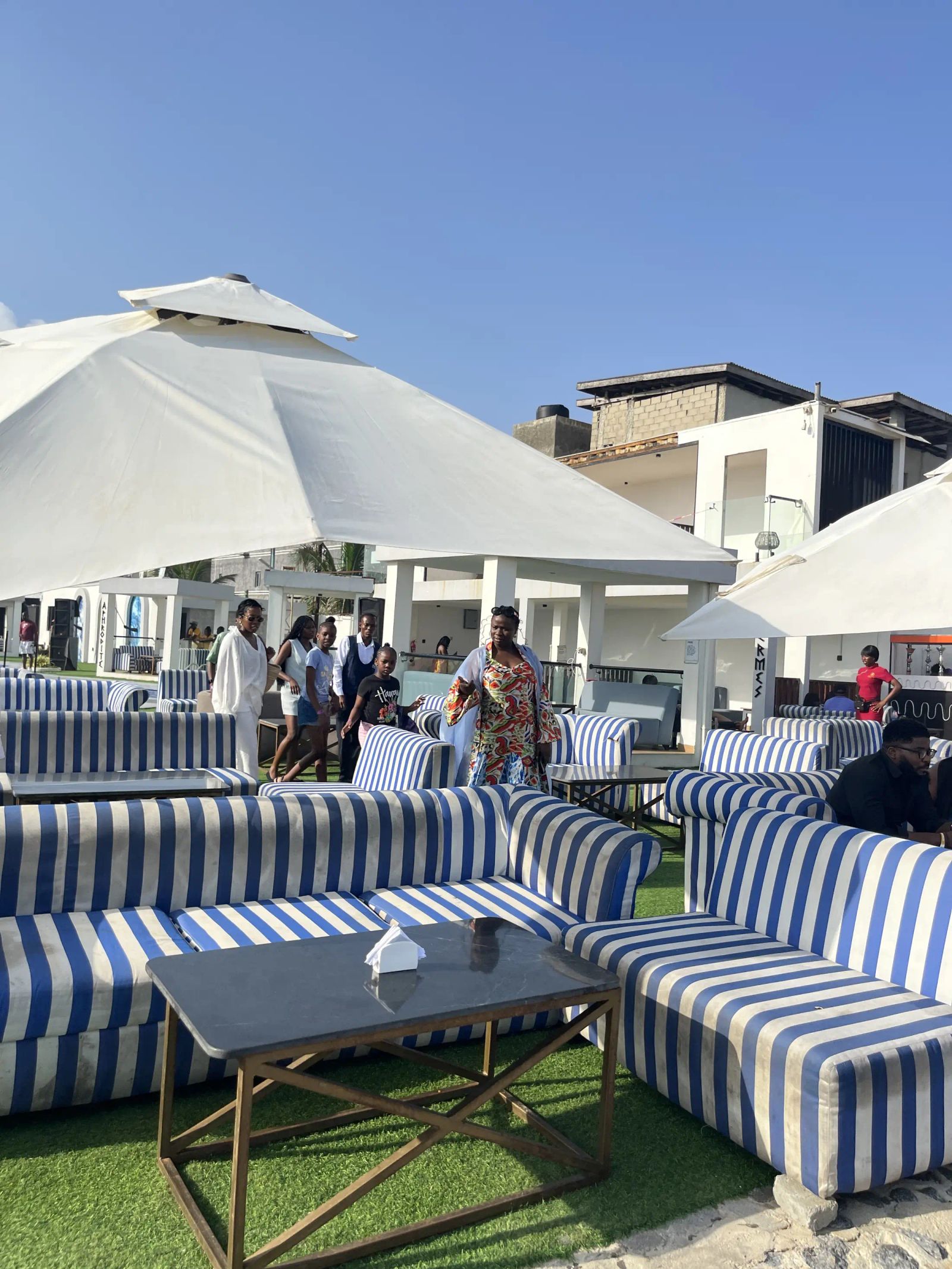Guests under white umbrellas on striped lounges