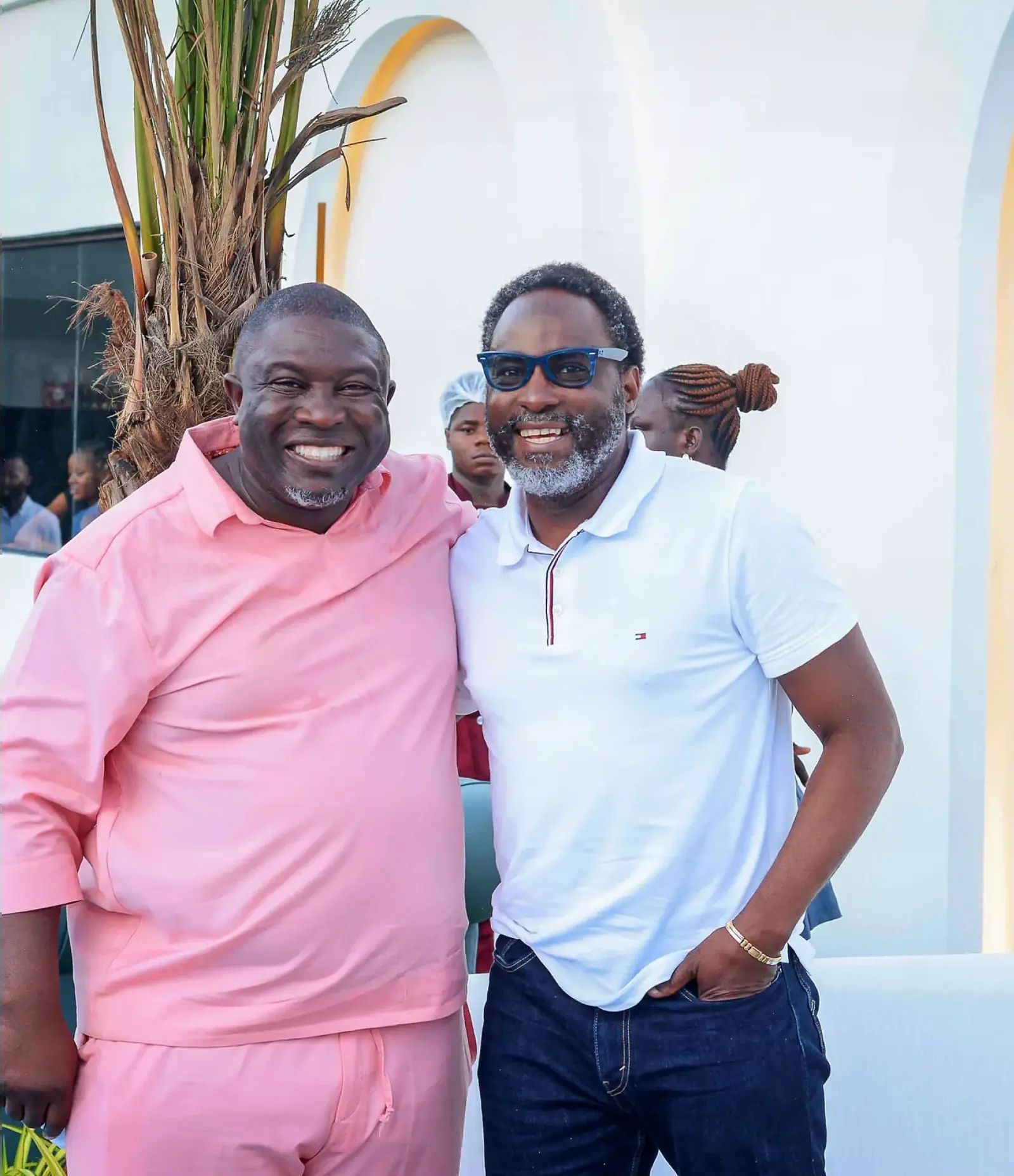 Two guests smiling by the white arch
